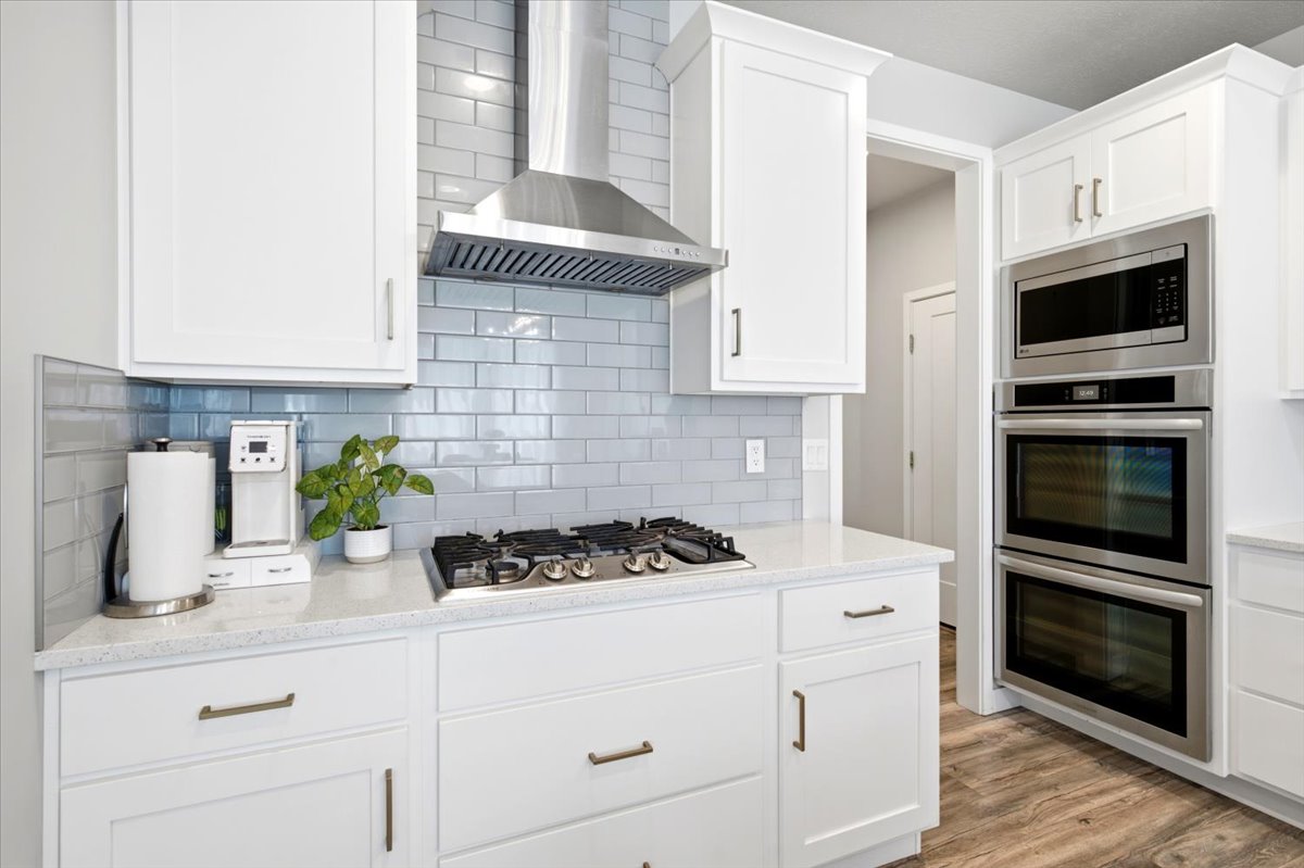 Contemporary kitchen featuring white shaker-style cabinetry, a subway tile backsplash, and quartz countertops
