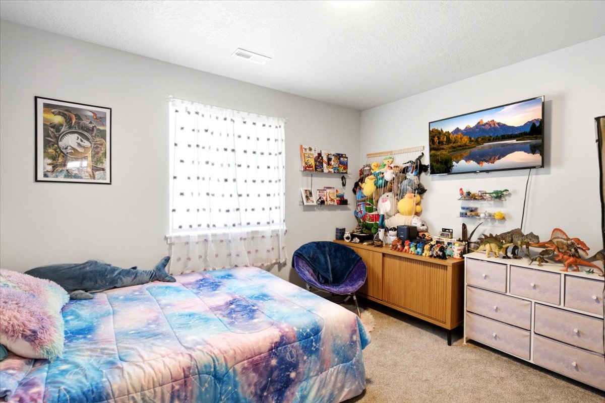 Carpeted room with a window featuring sheer white curtains