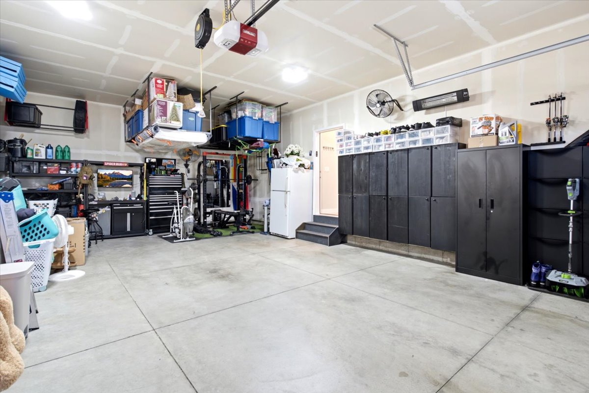 Spacious garage featuring concrete flooring, unpainted drywall, and overhead storage systems