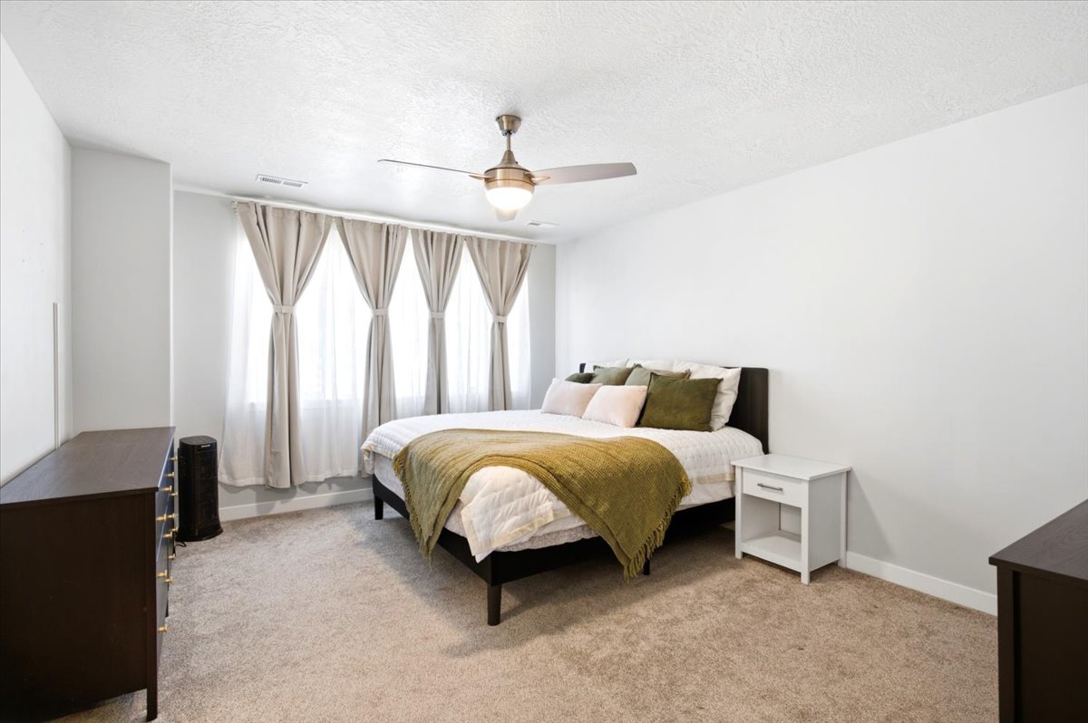 Spacious room featuring neutral carpeting, light-toned walls, and a ceiling fan with integrated lighting