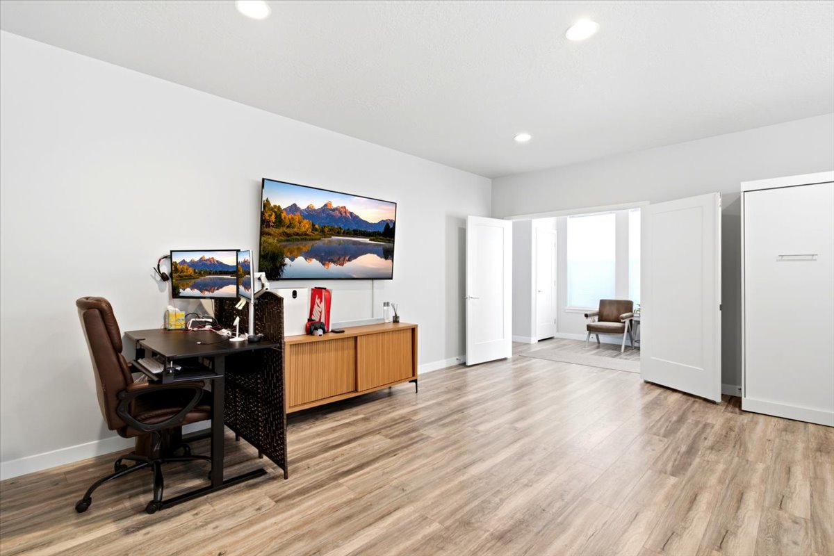 Spacious room featuring wood-finish flooring, recessed lighting, and a built-in wall unit