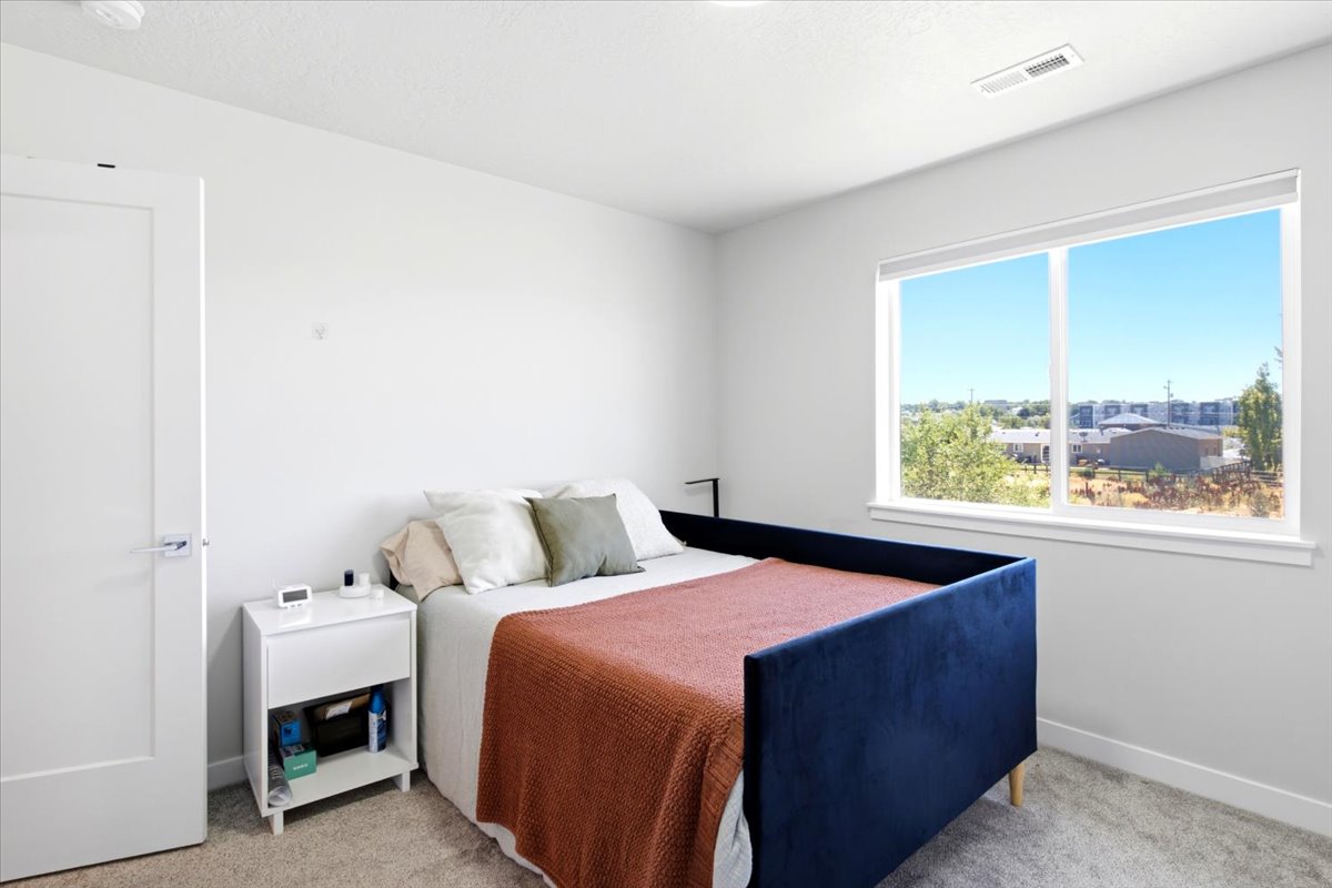 Bright room with a large window, light gray walls, and textured carpeting