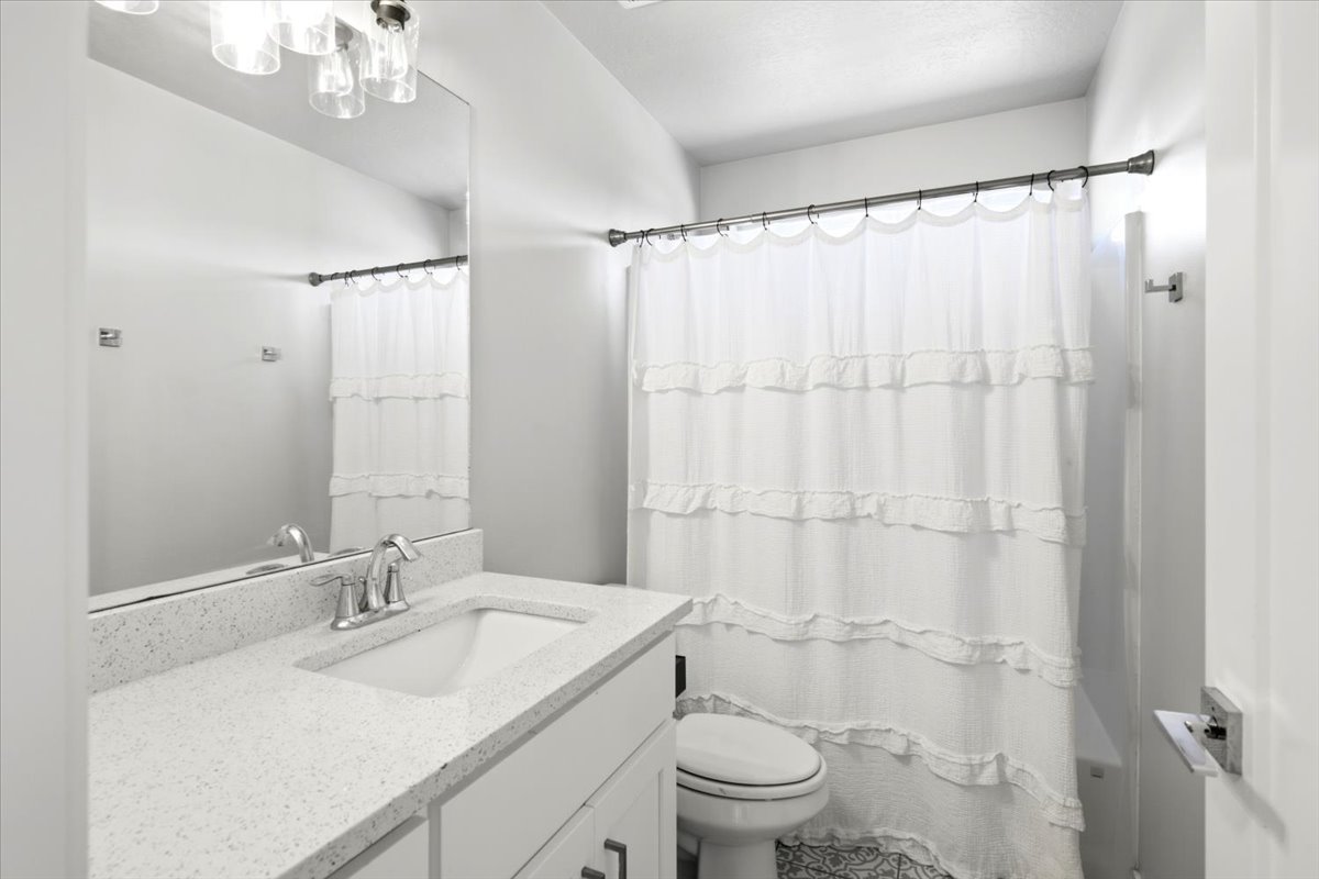 Bathroom featuring a modern vanity with integrated sink, speckled countertop, and brushed nickel faucet