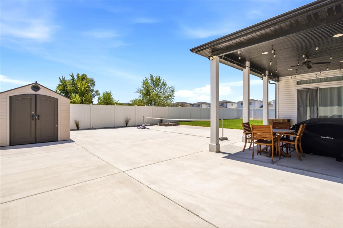 Expansive concrete patio area featuring a covered porch with recessed lighting and a ceiling fan