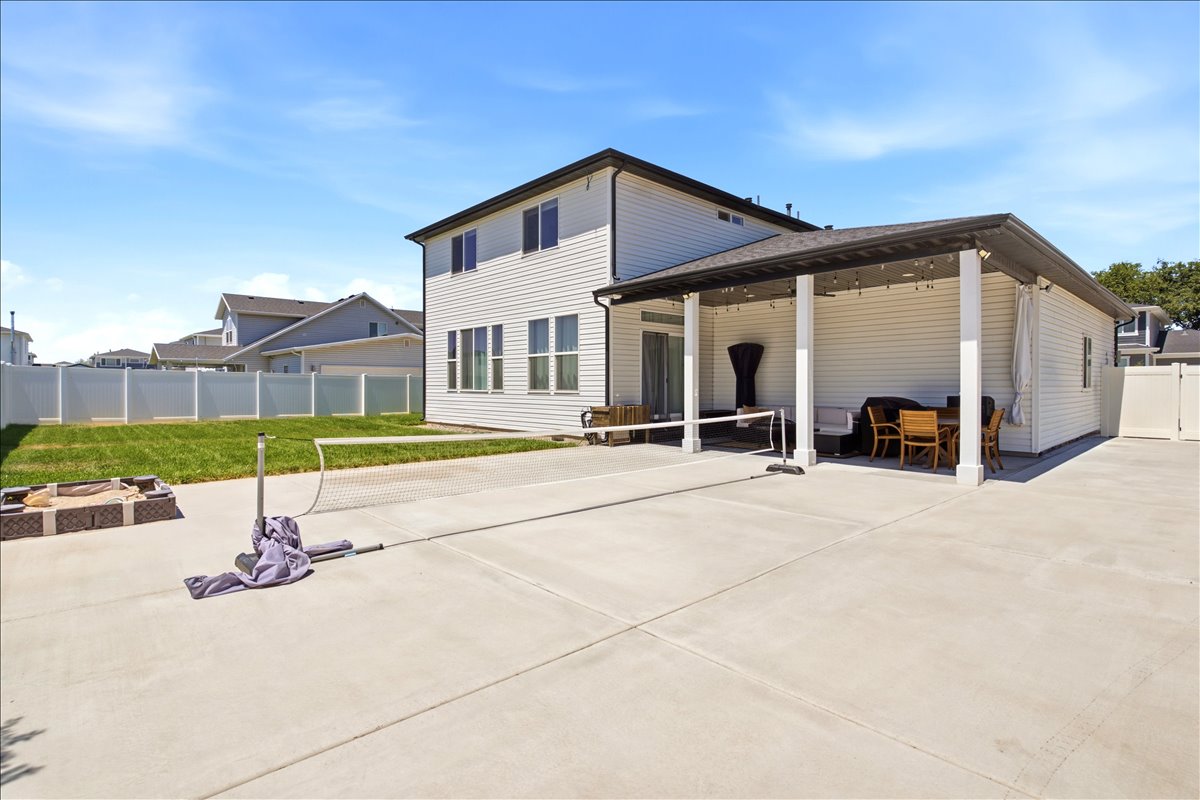 Expansive concrete patio featuring a covered outdoor living area with string lighting