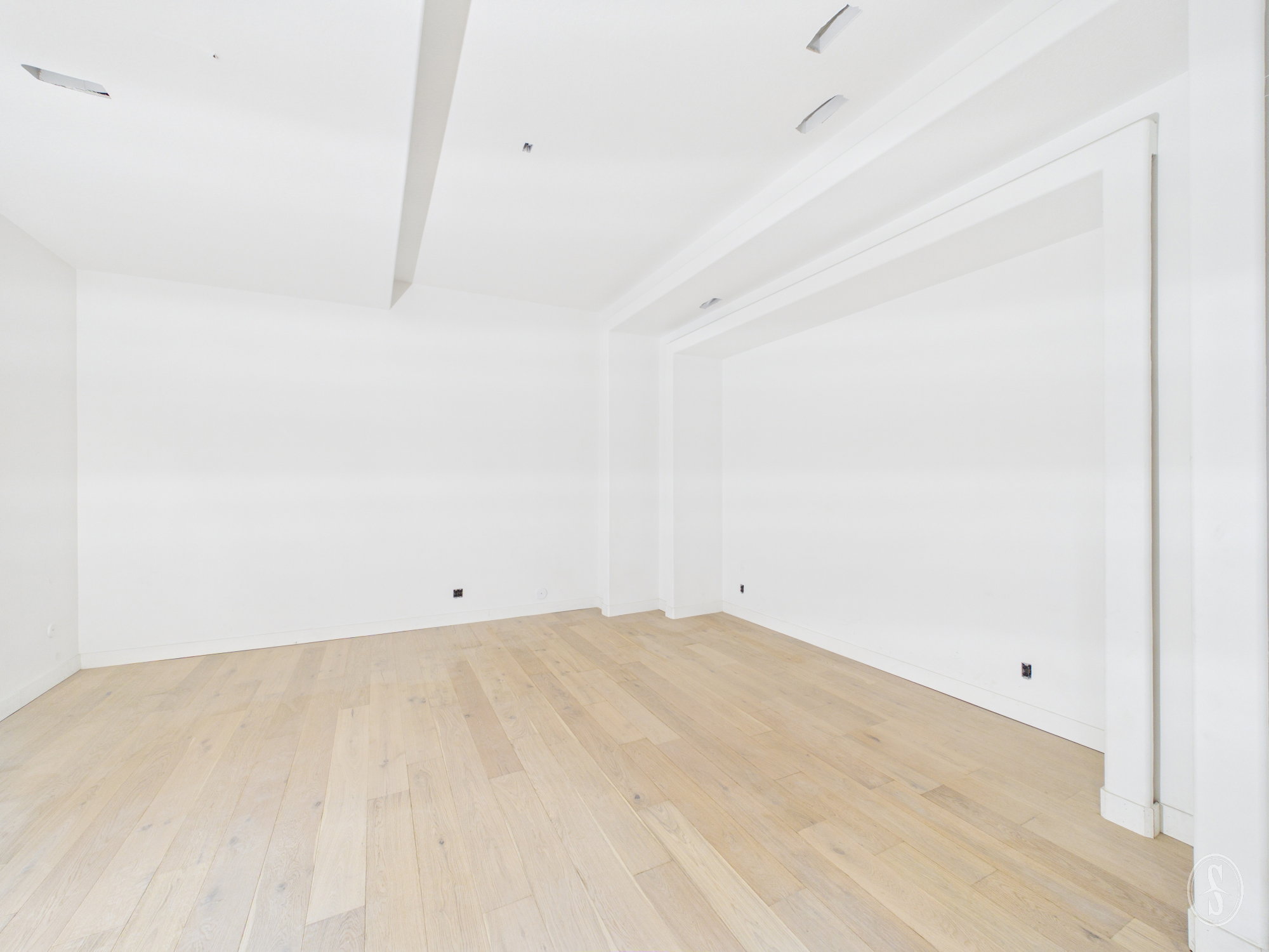 Spacious room featuring light wood-finish flooring, recessed ceiling lighting, and a wide cased opening