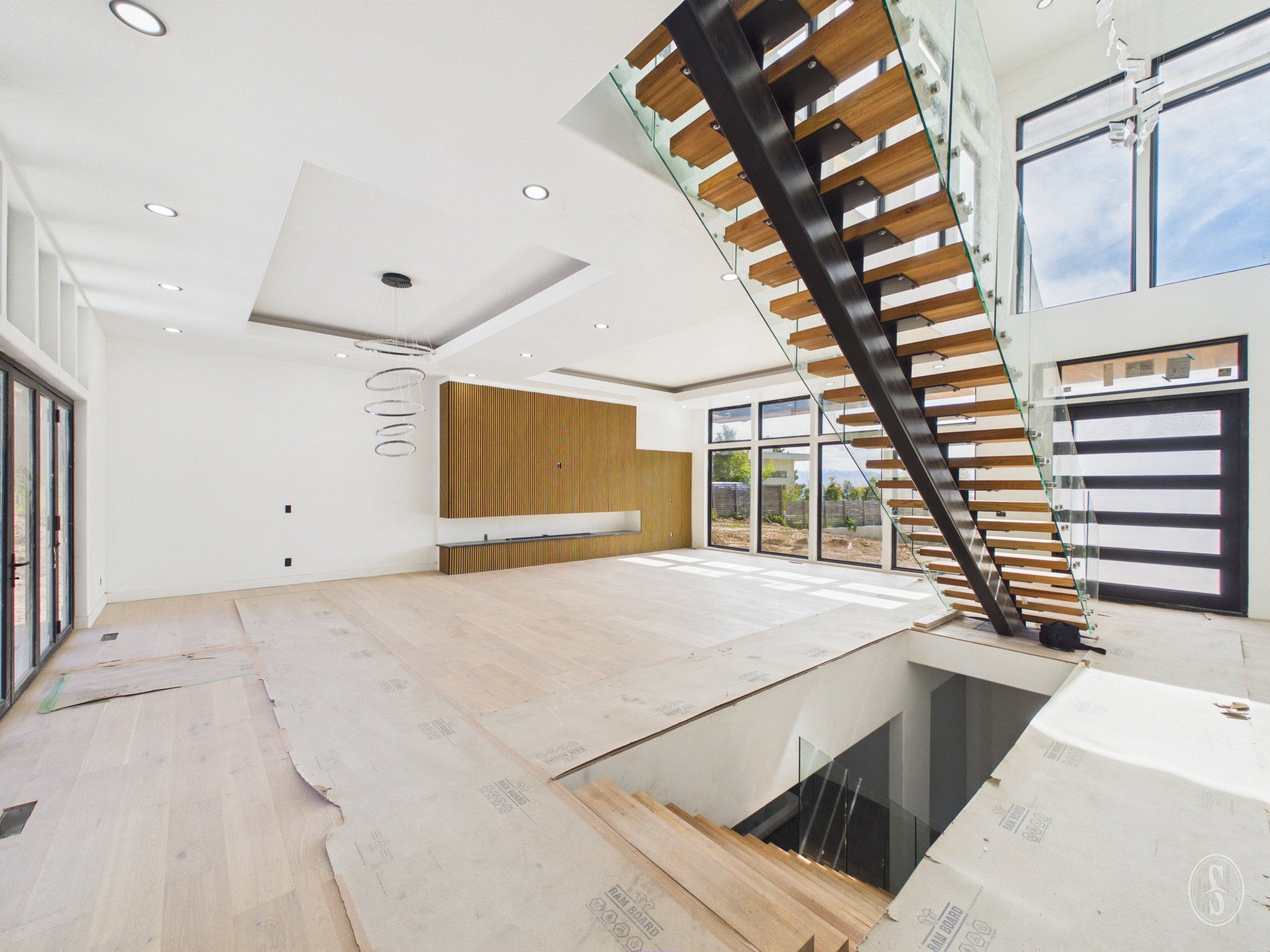 Grand entryway featuring a floating staircase with glass railings and wood treads