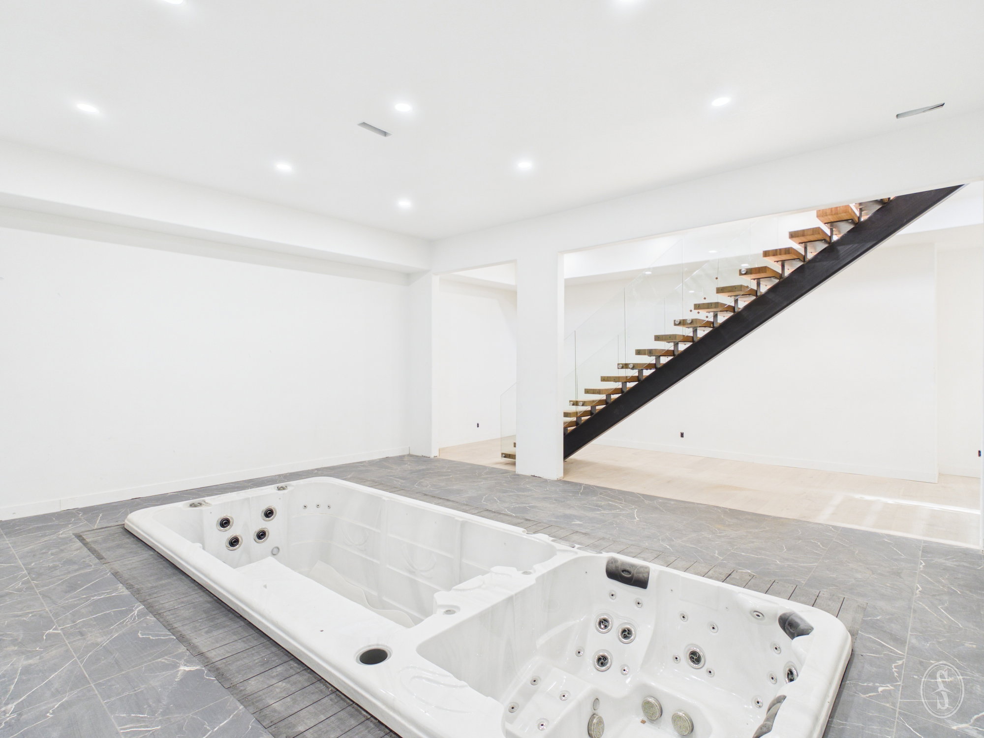 Indoor swim spa and hot tub with surrounding dark gray tile flooring