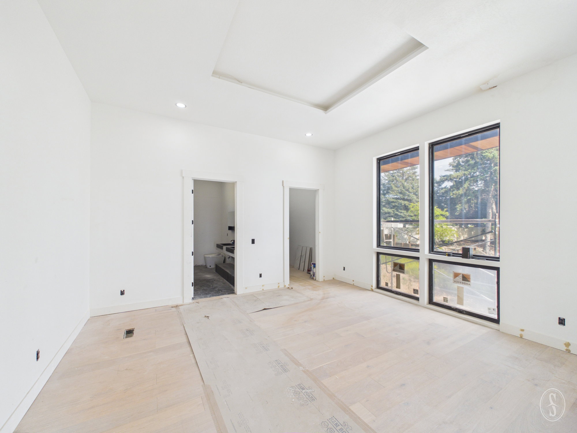Expansive room featuring light wood-finish flooring and a tray ceiling with recessed lighting