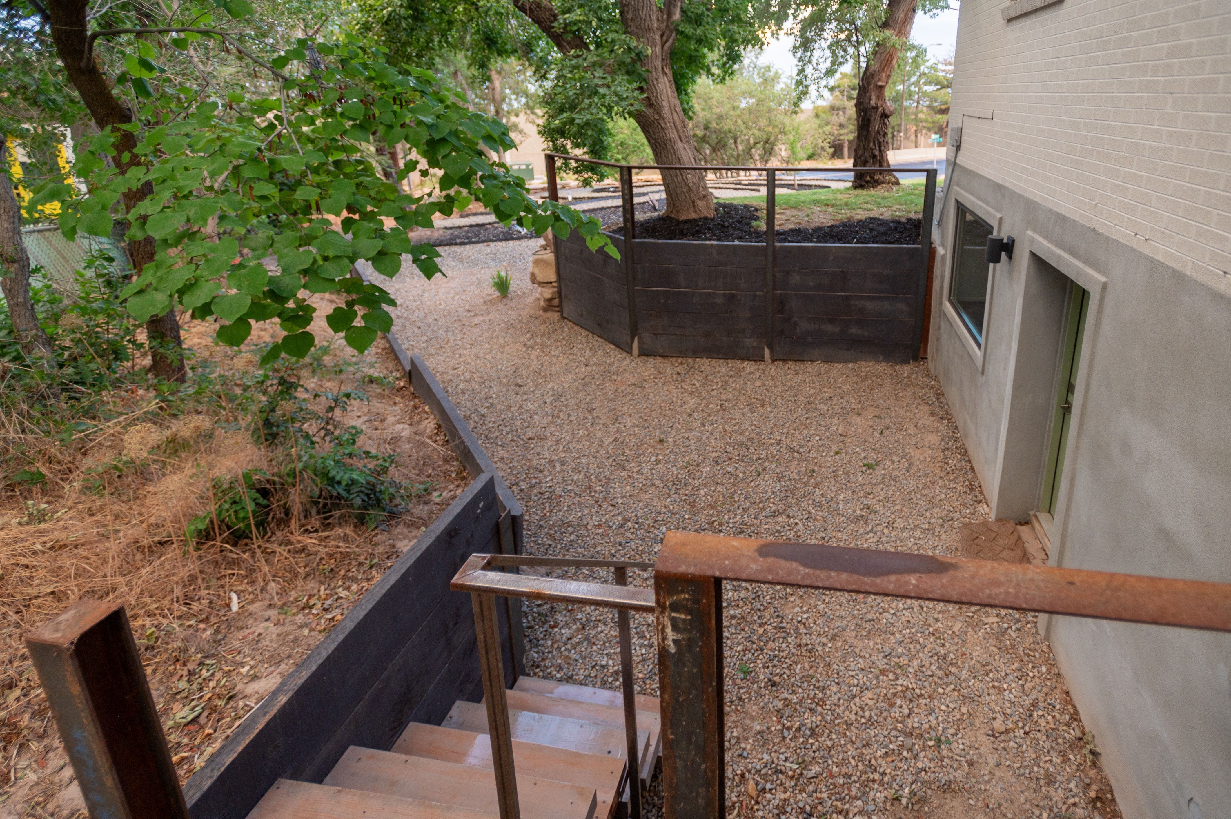 Outdoor gravel area bordered by a concrete wall with a window and door