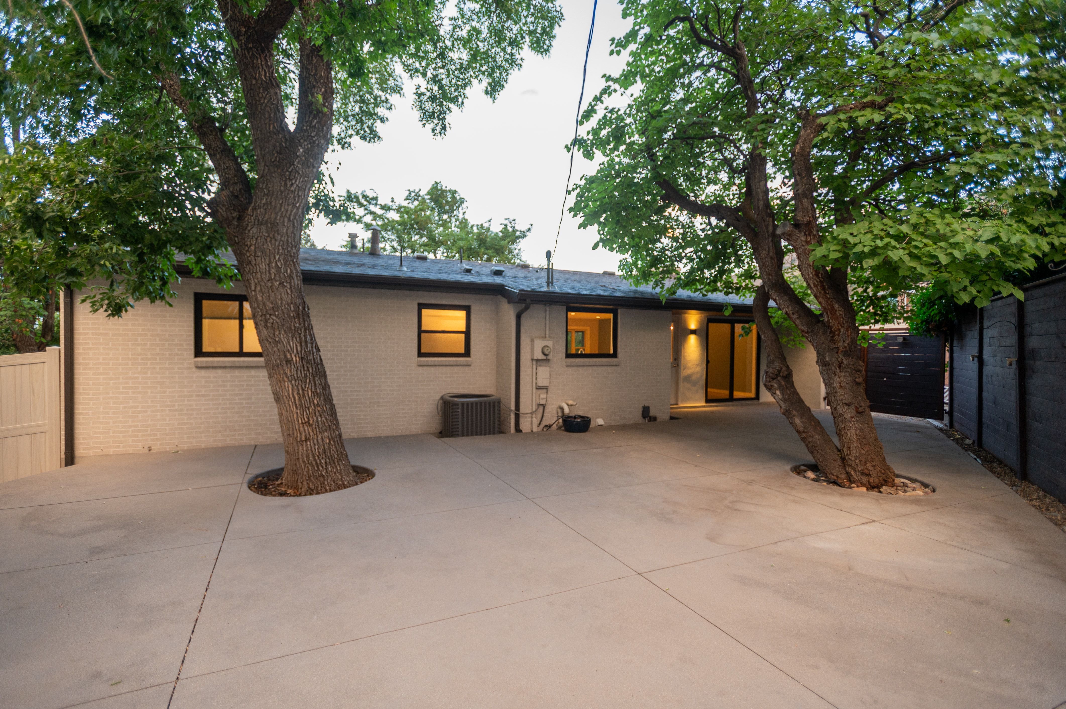 Expansive concrete patio area with two mature trees