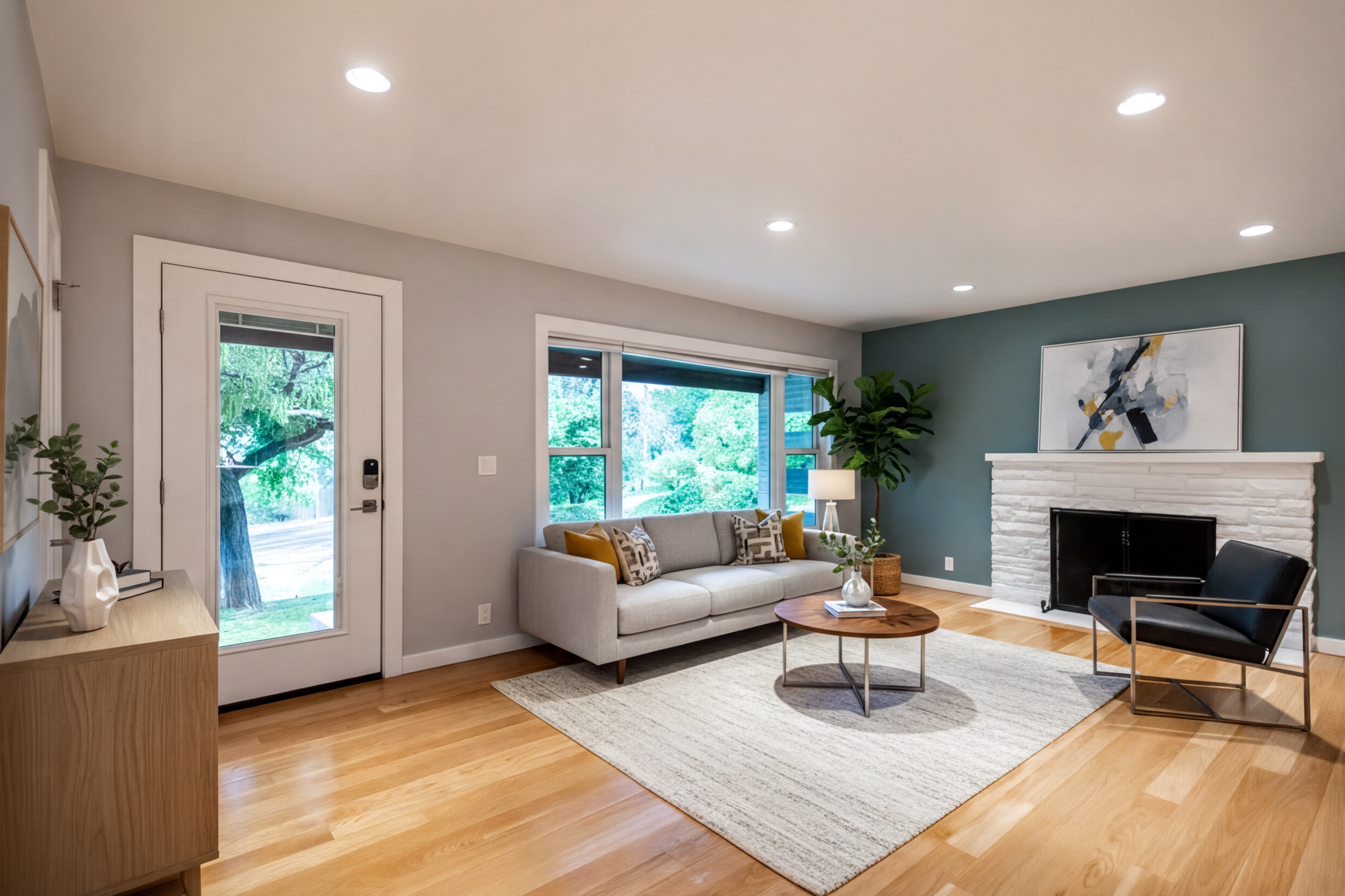 Living room with light wood-finish flooring, recessed lighting, and a white stone-clad fireplace