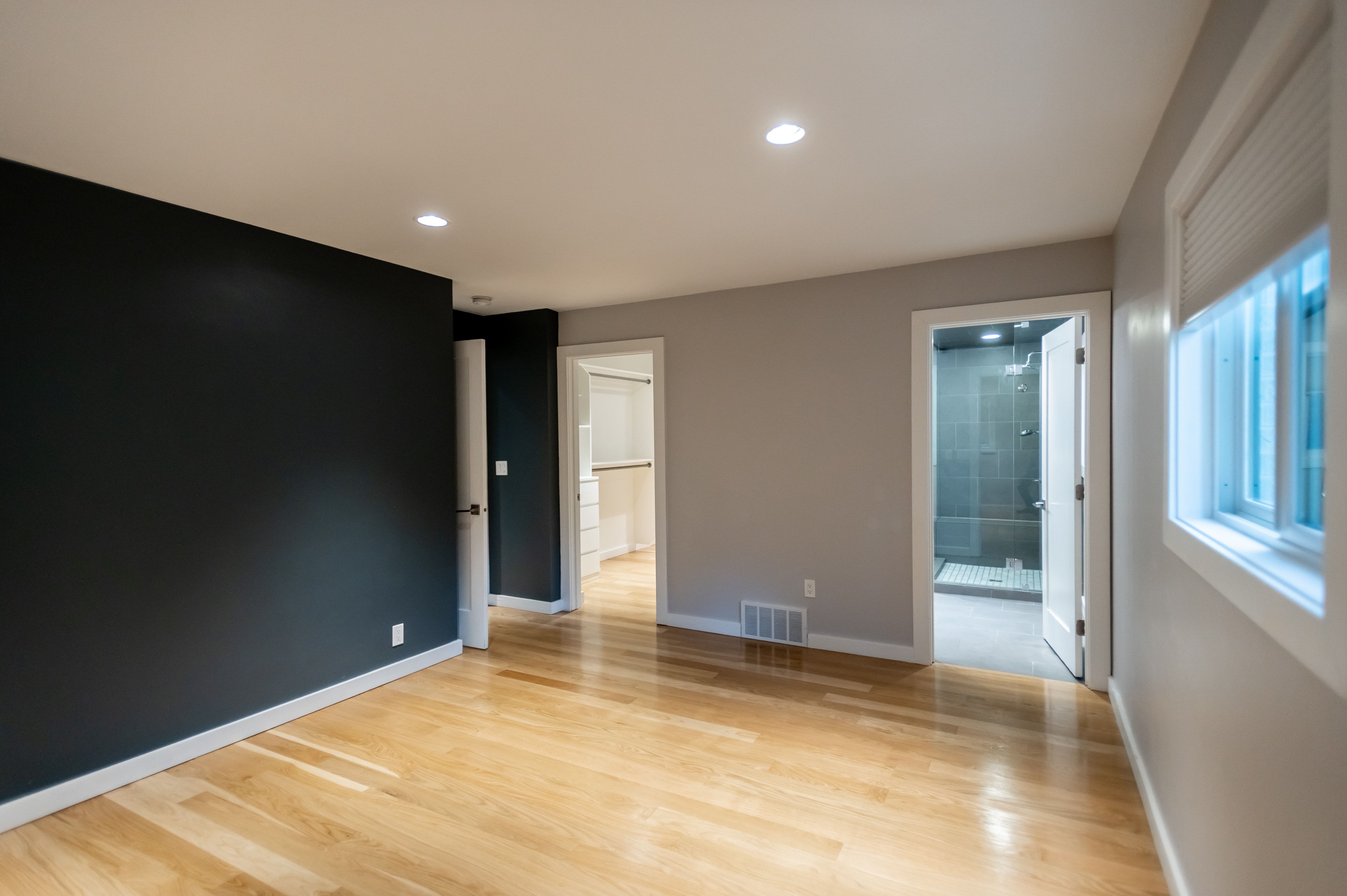 Spacious room featuring wood-finish flooring, recessed lighting, and a dark accent wall