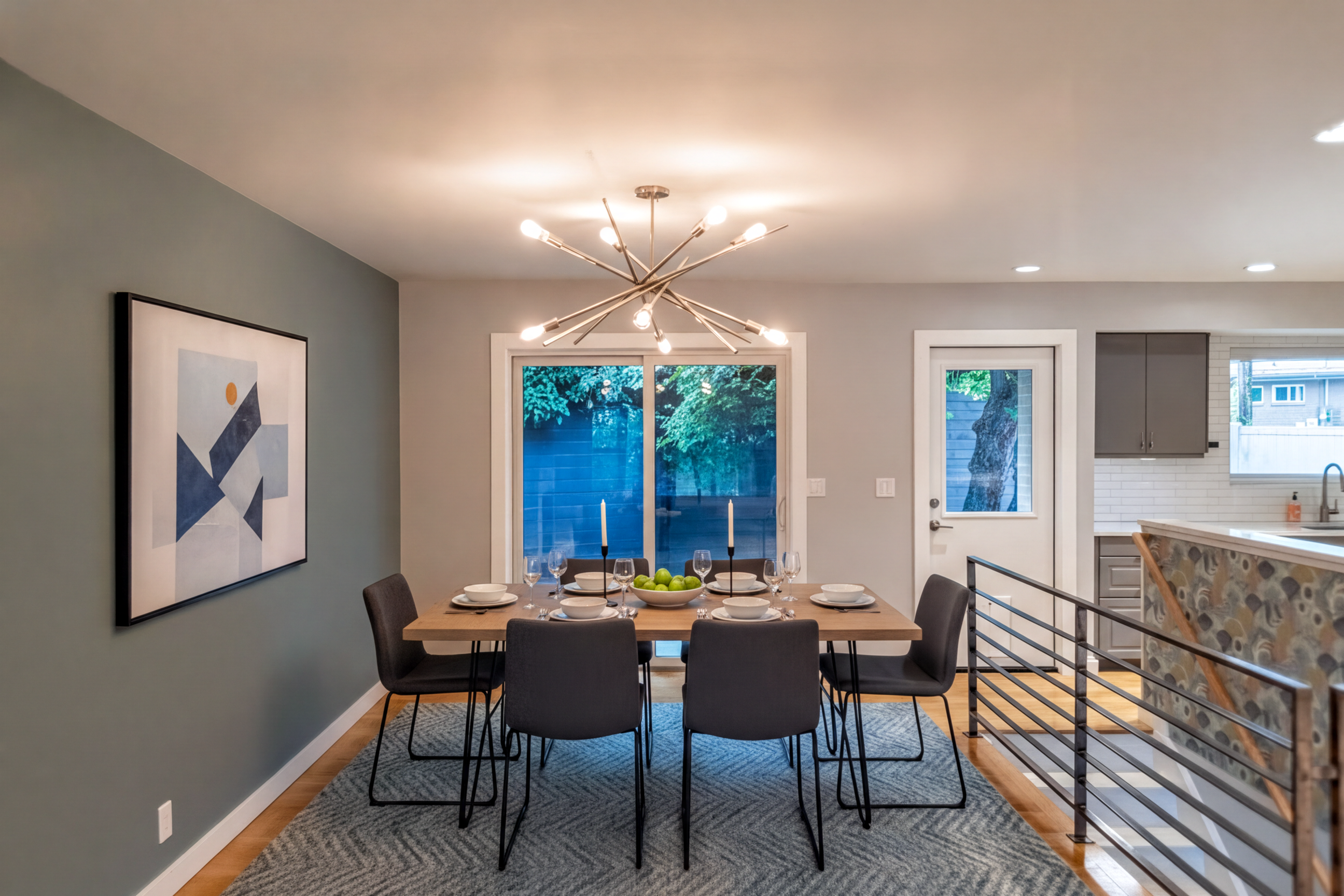 Dining area featuring a contemporary chandelier, wood-finish flooring, and a sliding glass door. Virtually staged