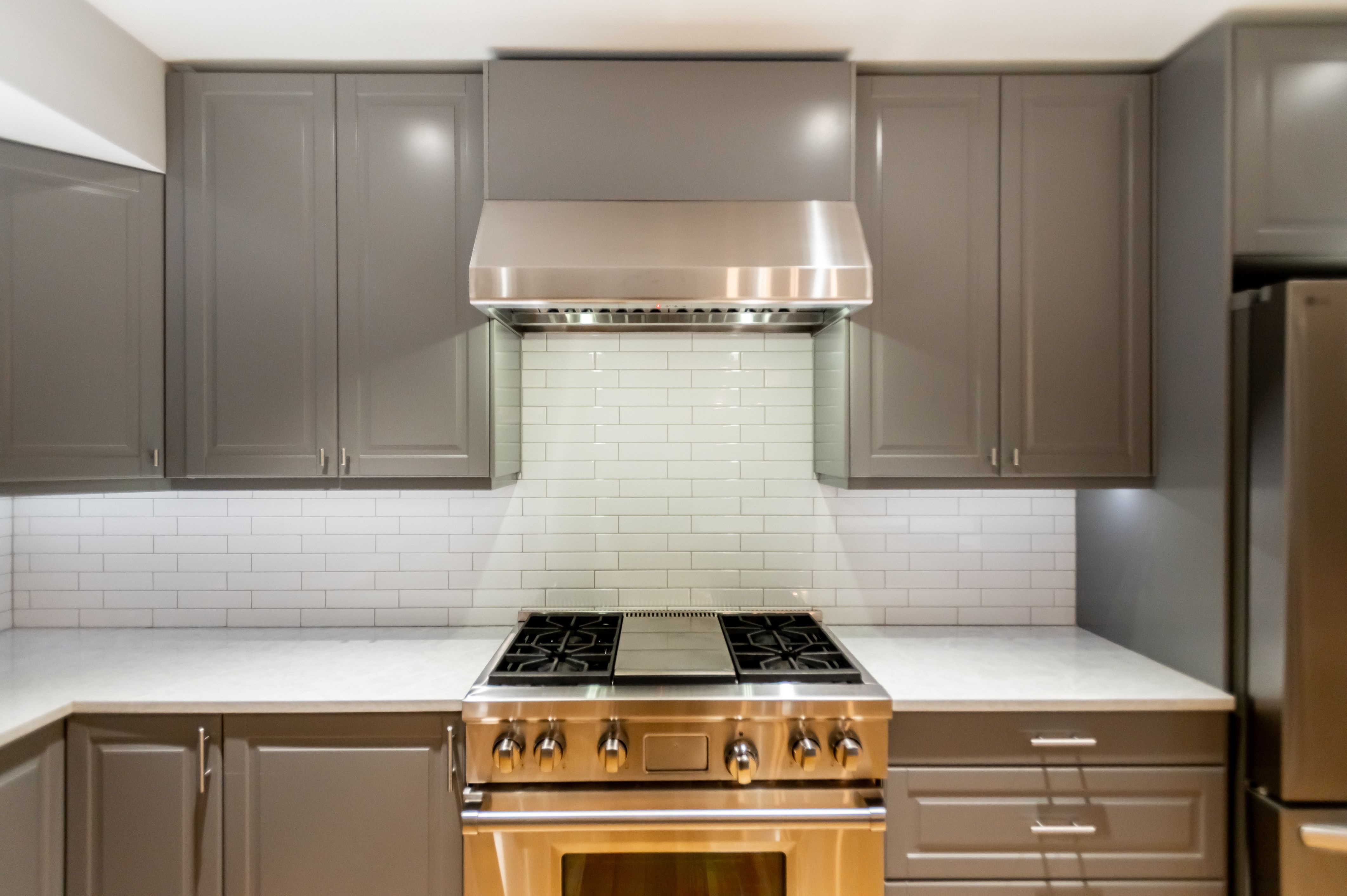 Modern kitchen featuring a stainless steel gas range with coordinating vent hood