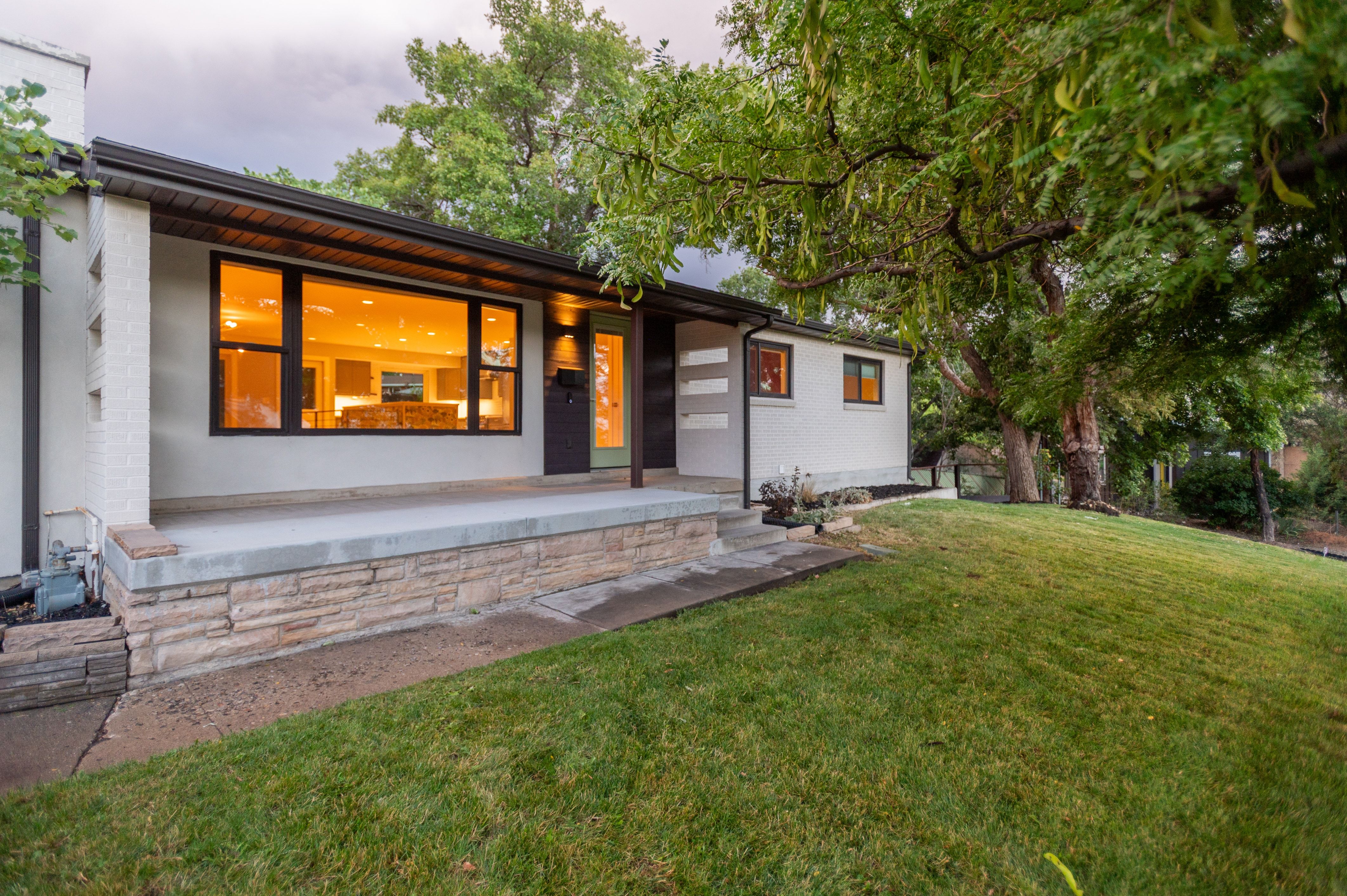 Contemporary facade featuring a large front window, stone-accented foundation, and a covered entry