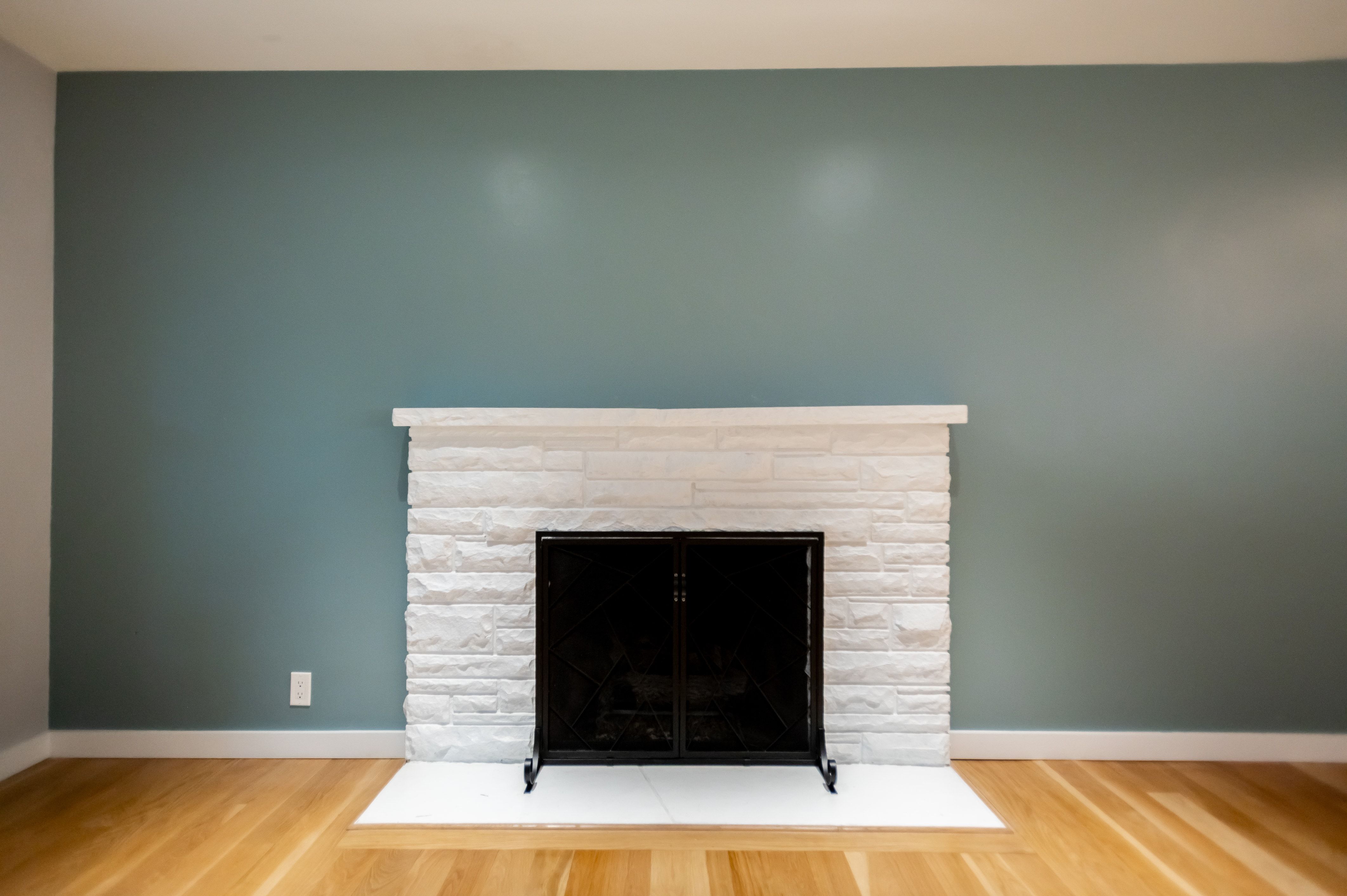 Fireplace featuring a white stacked stone surround, a black metal screen, and a white hearth