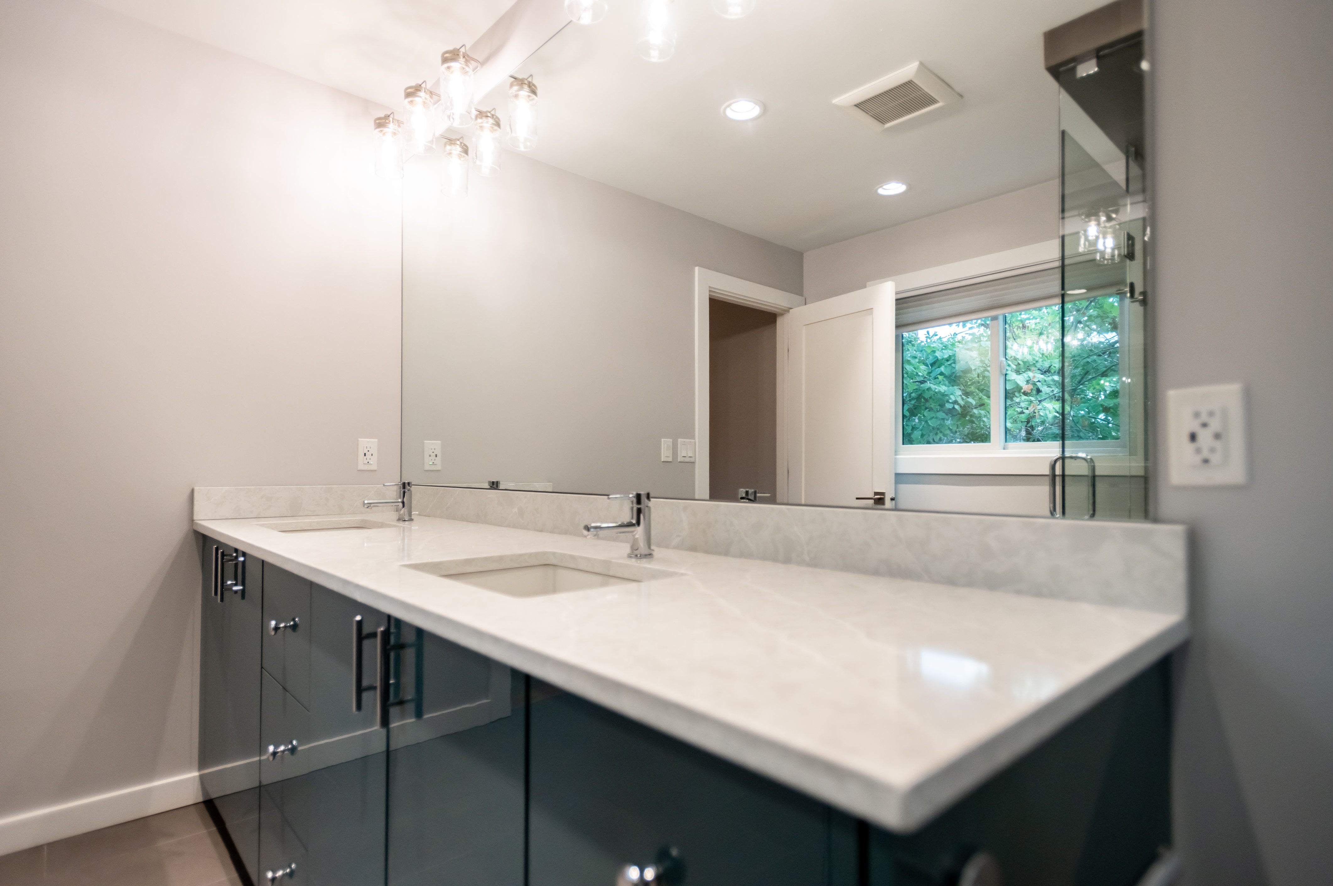 Double vanity featuring integrated sinks, light-toned countertops, and dark cabinetry with modern pulls