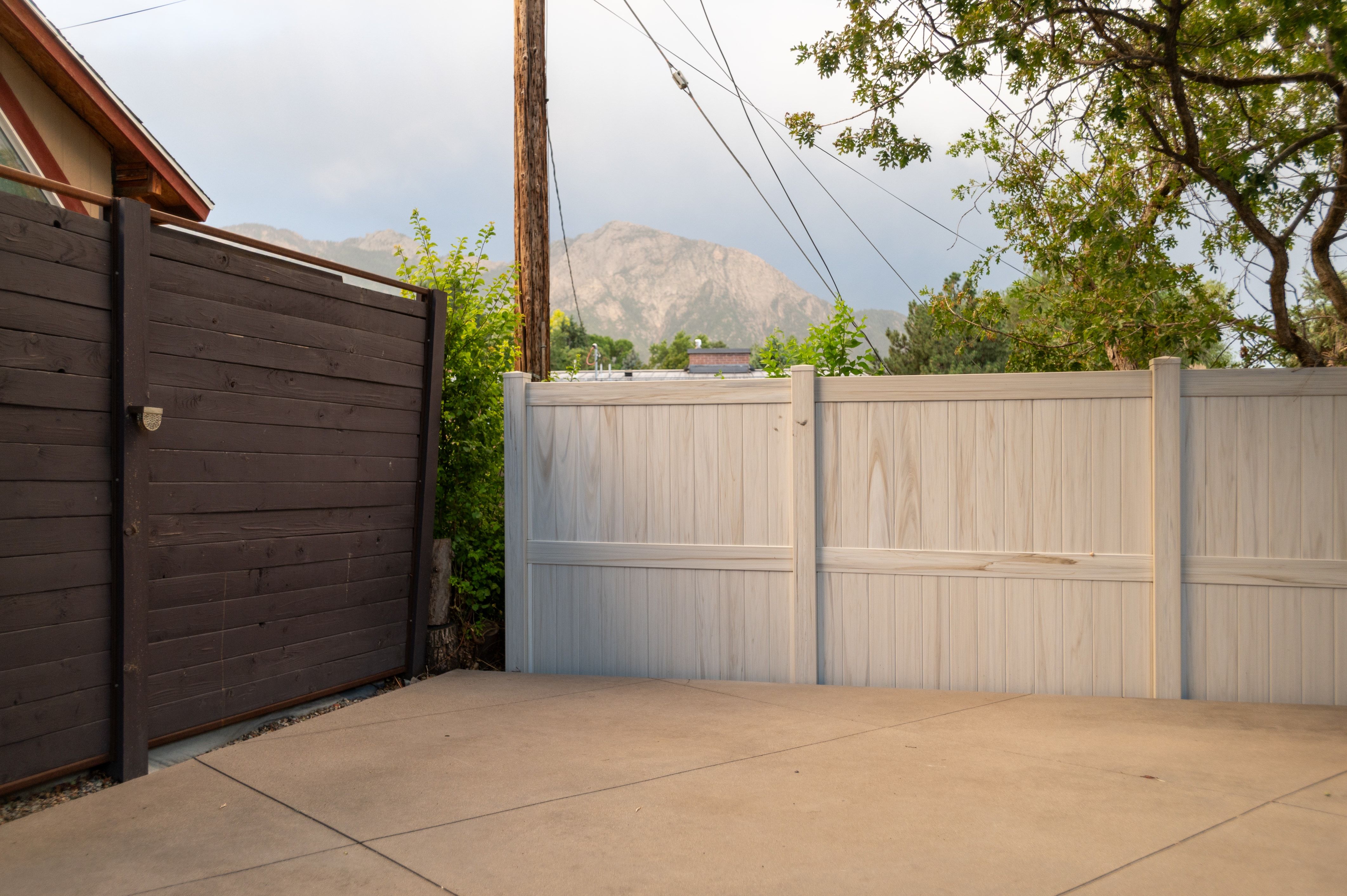 Paved concrete surface bordered by a dark wood-finish fence and a light wood-finish fence