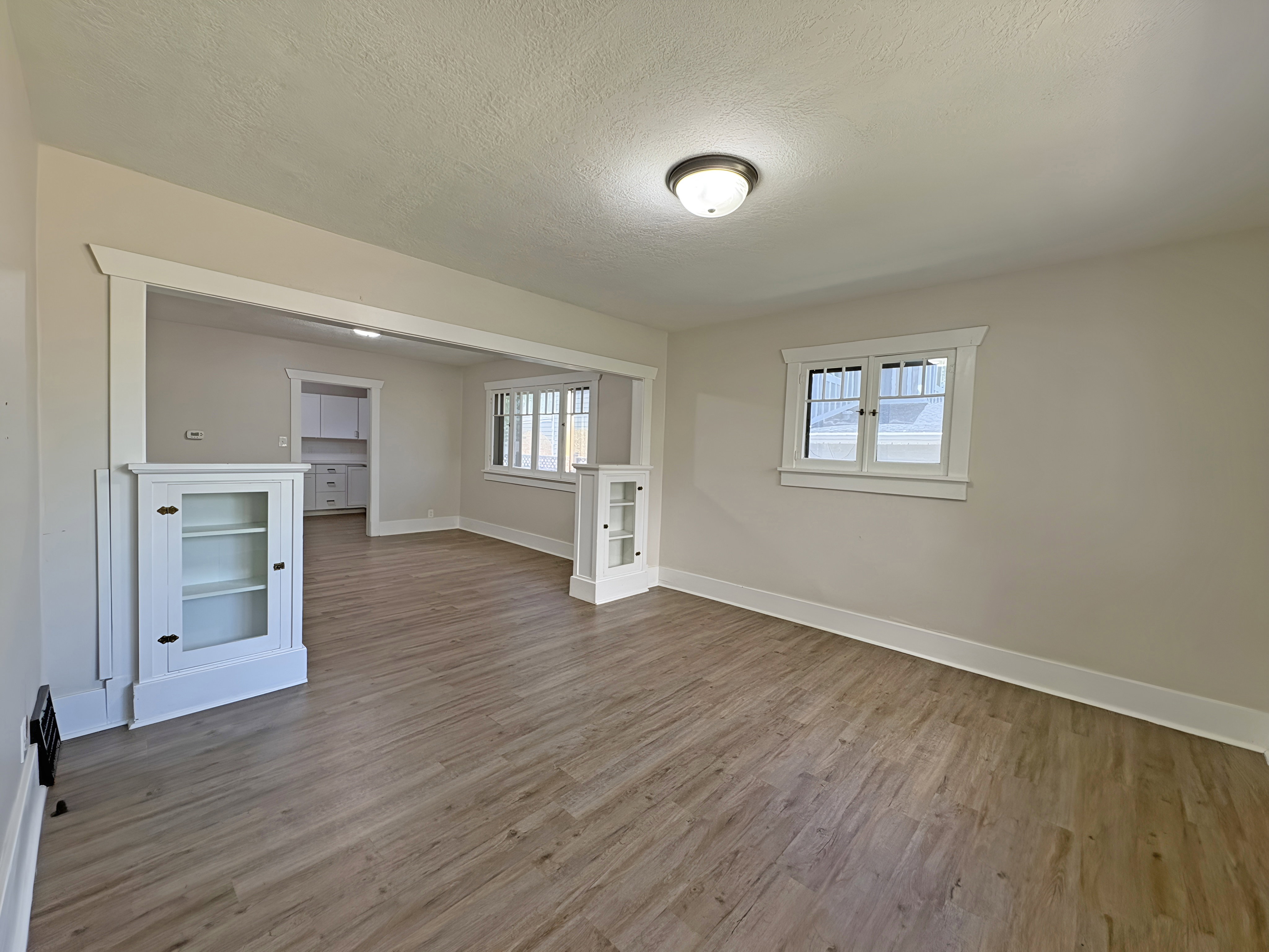 Spacious room featuring wood-finish flooring, light-toned walls, and white trim
