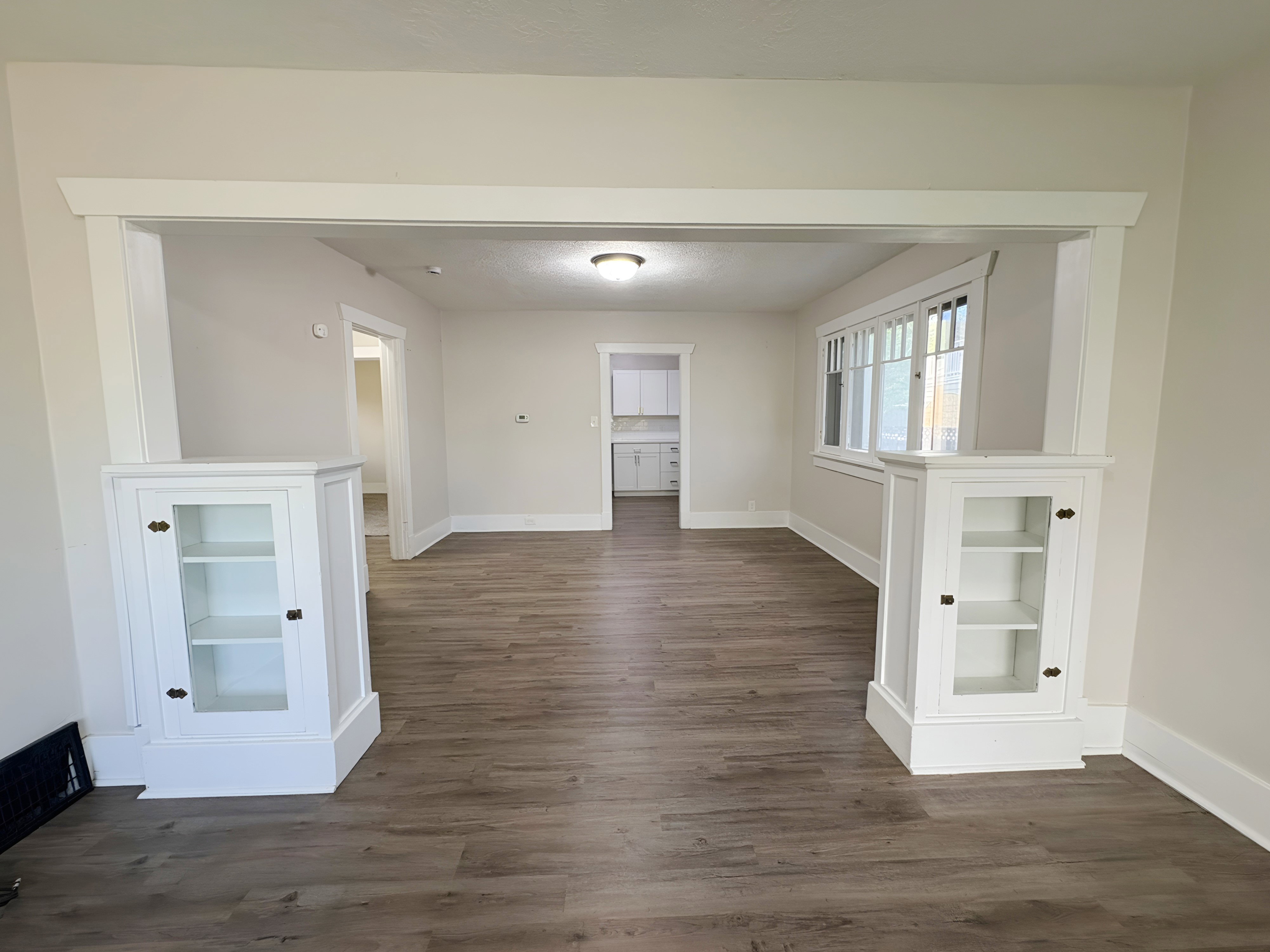 Archway entry with built-in display cabinets, wood-finish flooring, and neutral wall tones