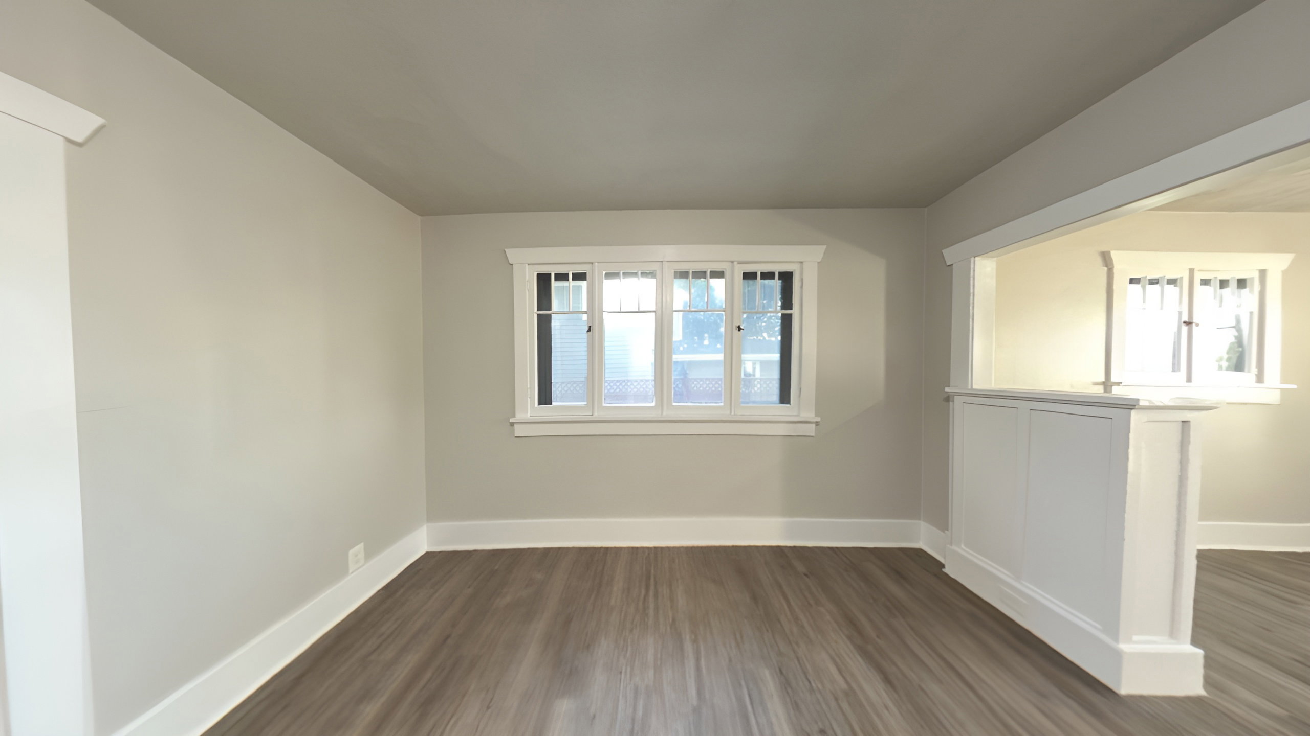Bright interior space featuring wood-finish flooring, light gray walls, white trim, and a multi-pane window