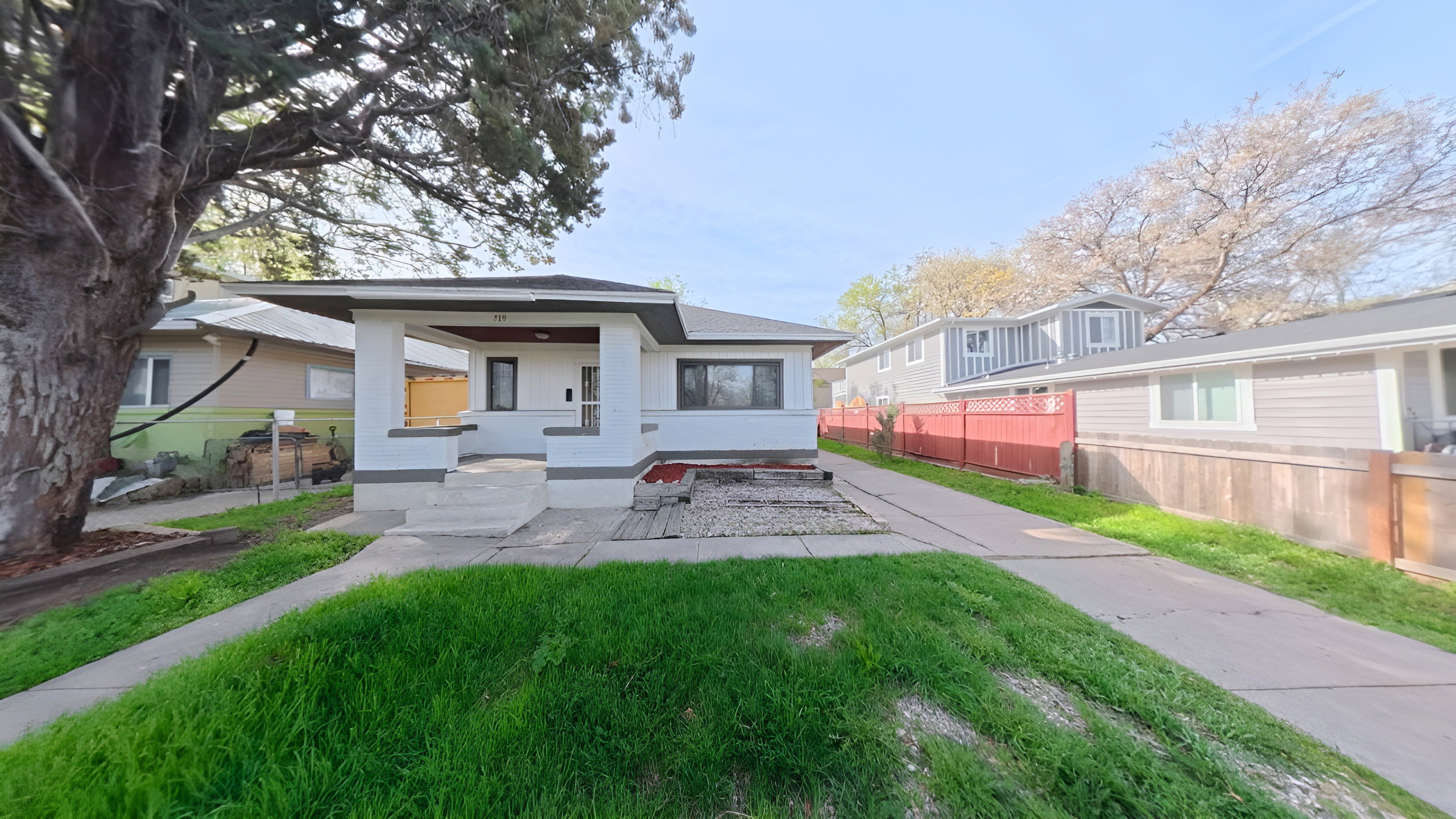 White exterior residence featuring a covered front porch, concrete pathway, and an extended driveway