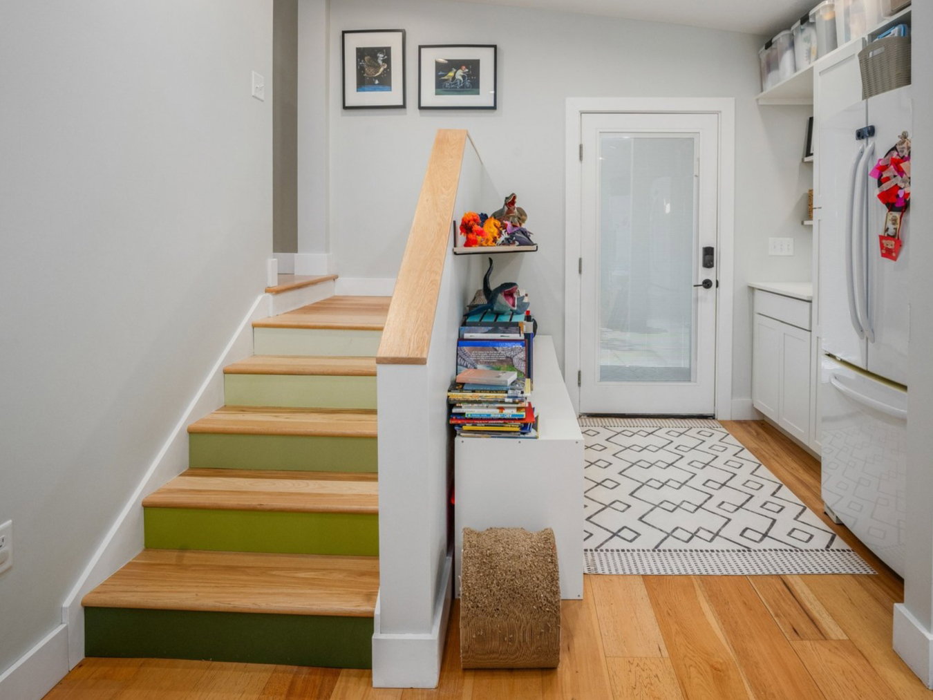 Hardwood flooring extends throughout this space featuring recessed lighting, a staircase with painted risers and natural wood treads, and built-in shelving