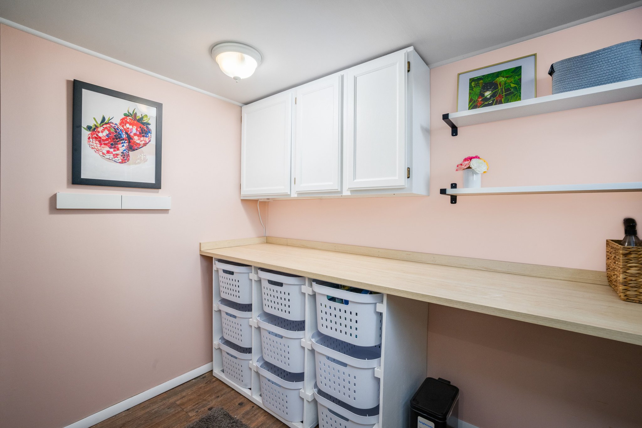 Laundry area featuring a wood-finish countertop, white upper cabinetry, and integrated storage shelving