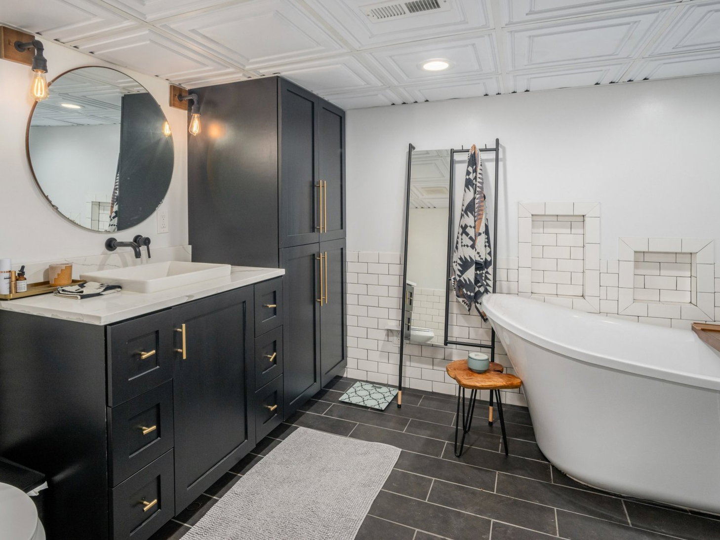 Bathroom featuring a black vanity with gold-tone hardware, a rectangular vessel sink, and a large circular mirror