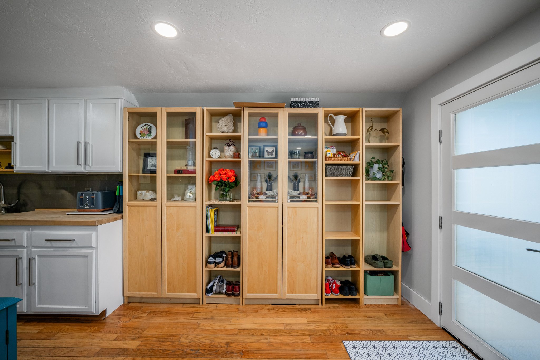Custom built-in shelving and cabinetry with glass-front display sections