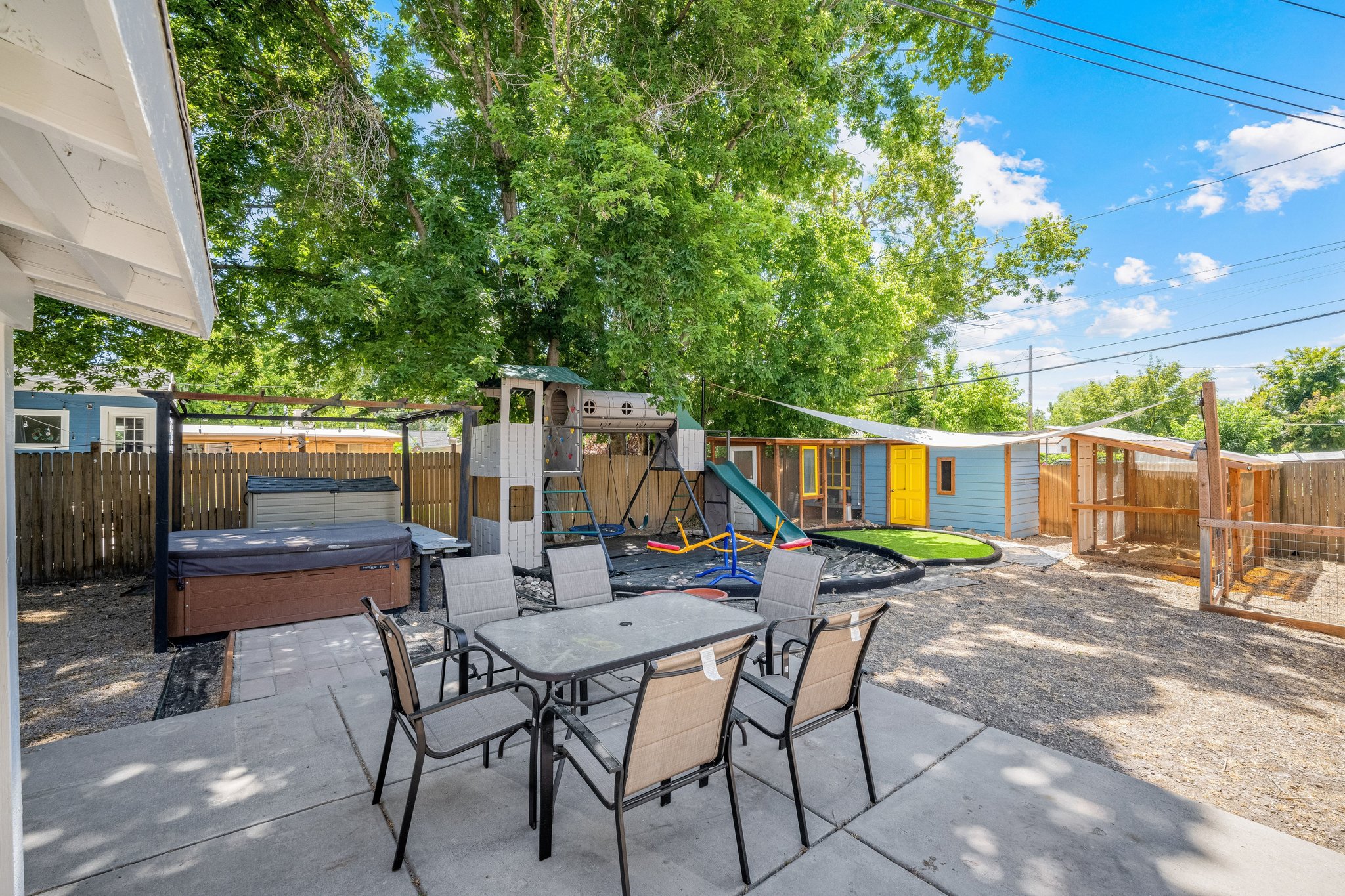 Expansive outdoor living area featuring a concrete patio, hot tub, and gravel landscaping