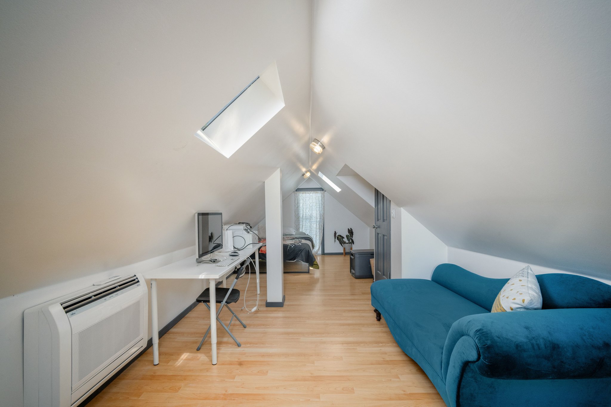 Attic space with light wood-finish flooring, two skylights, and sloped ceilings