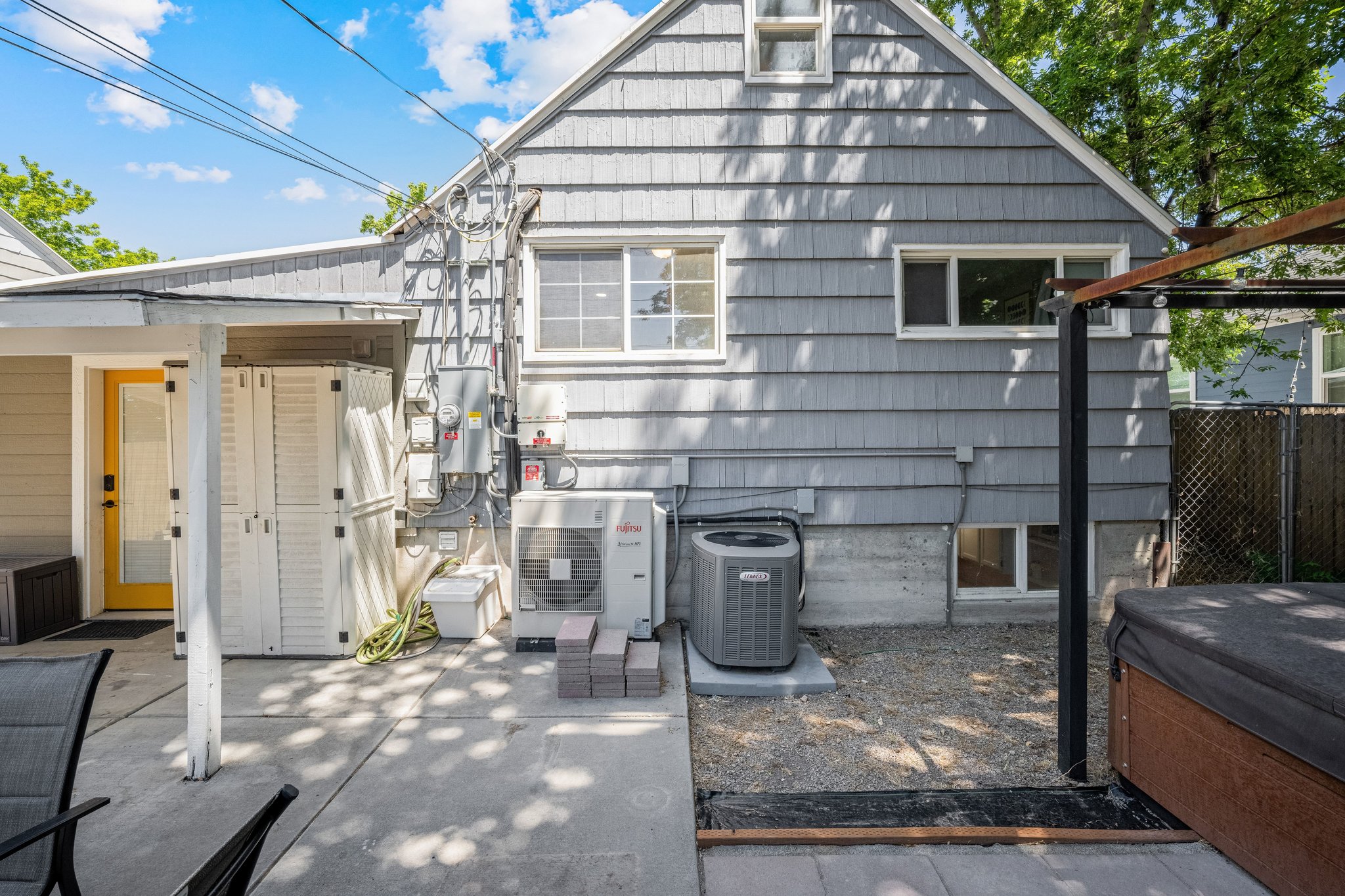 Rear facade with gray shingle siding and a yellow exterior door
