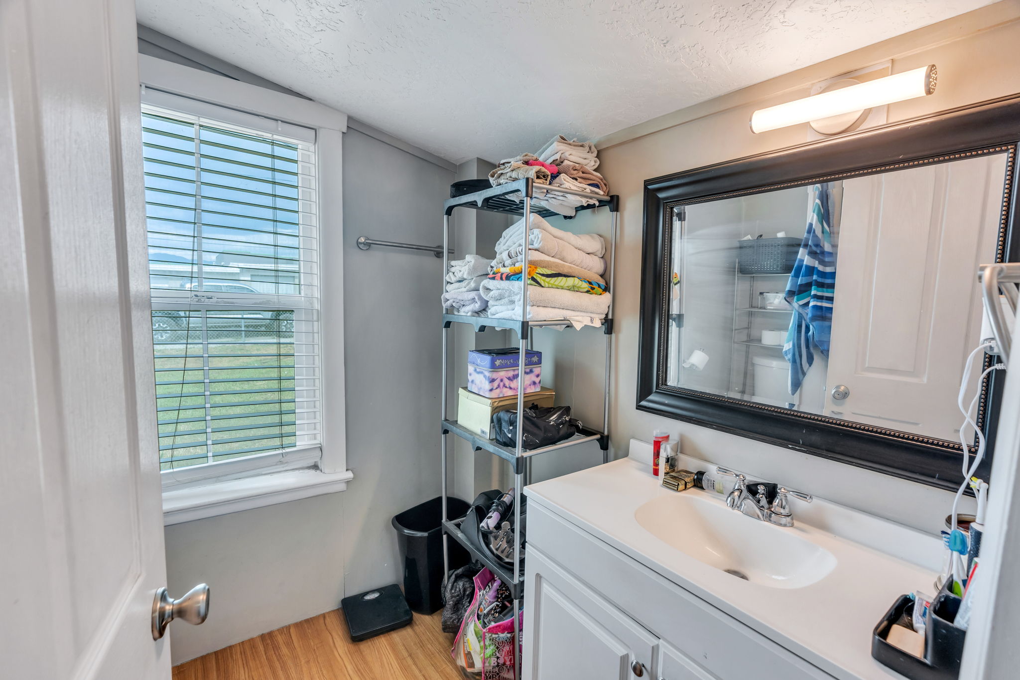 Bathroom vanity featuring a single basin sink, white cabinetry, and a large framed mirror with overhead lighting