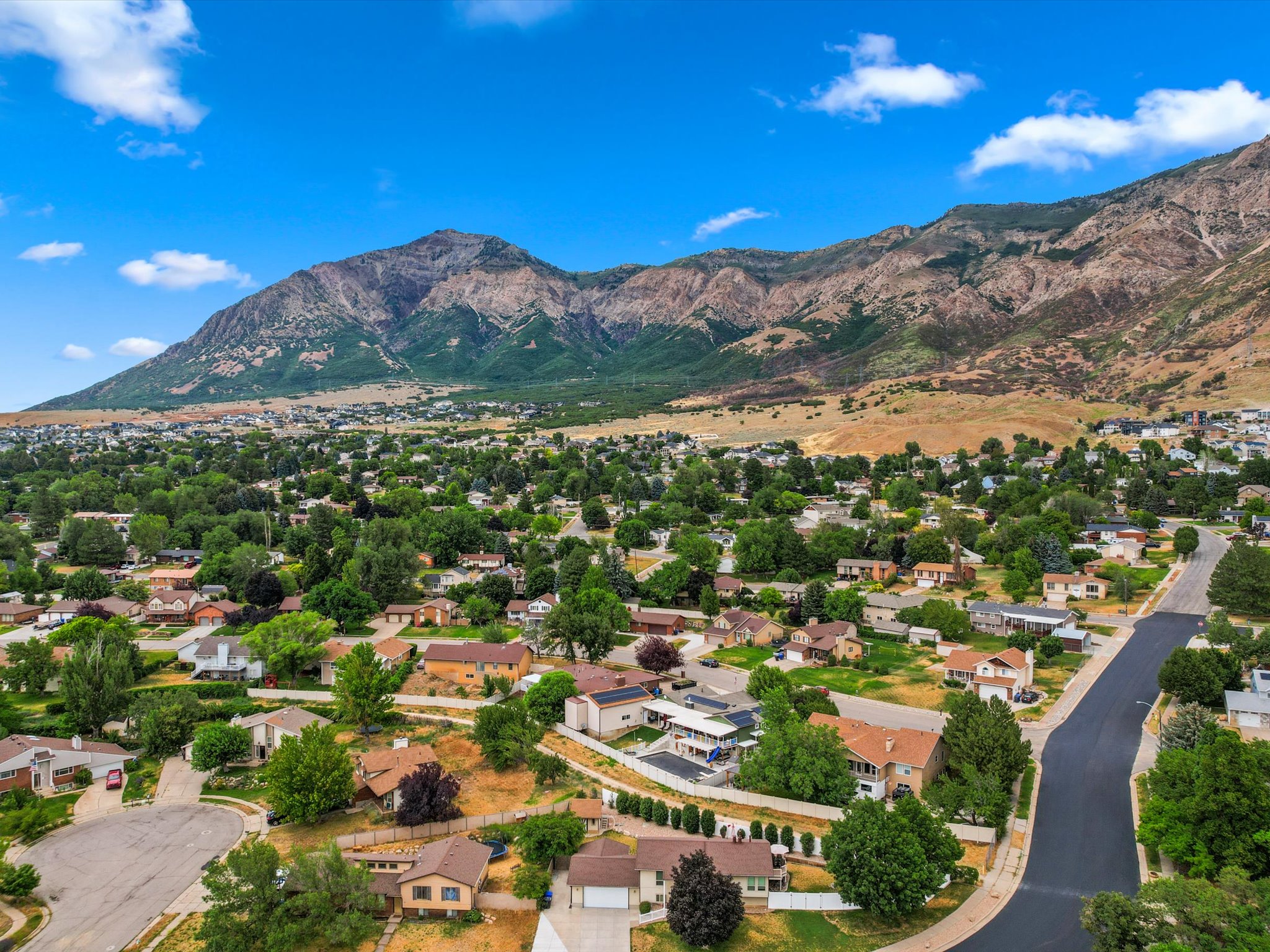 Expansive aerial panorama showcasing a residential community situated at the base of a significant mountain range