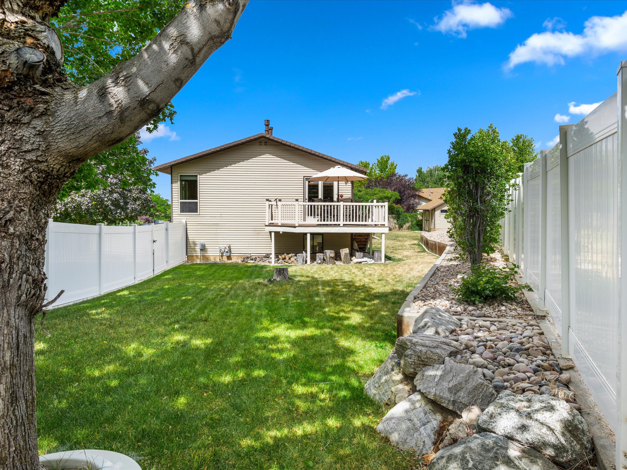 Expansive backyard with a manicured lawn, white privacy fencing, and a composite deck