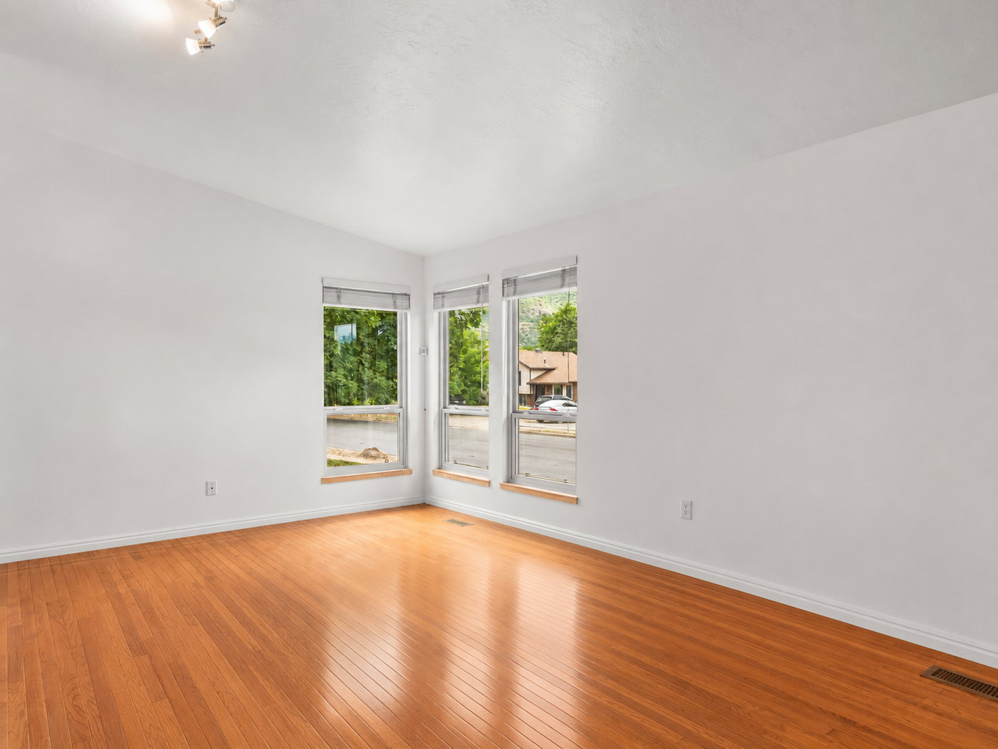 Bright interior space featuring wood flooring, white baseboards, and white walls