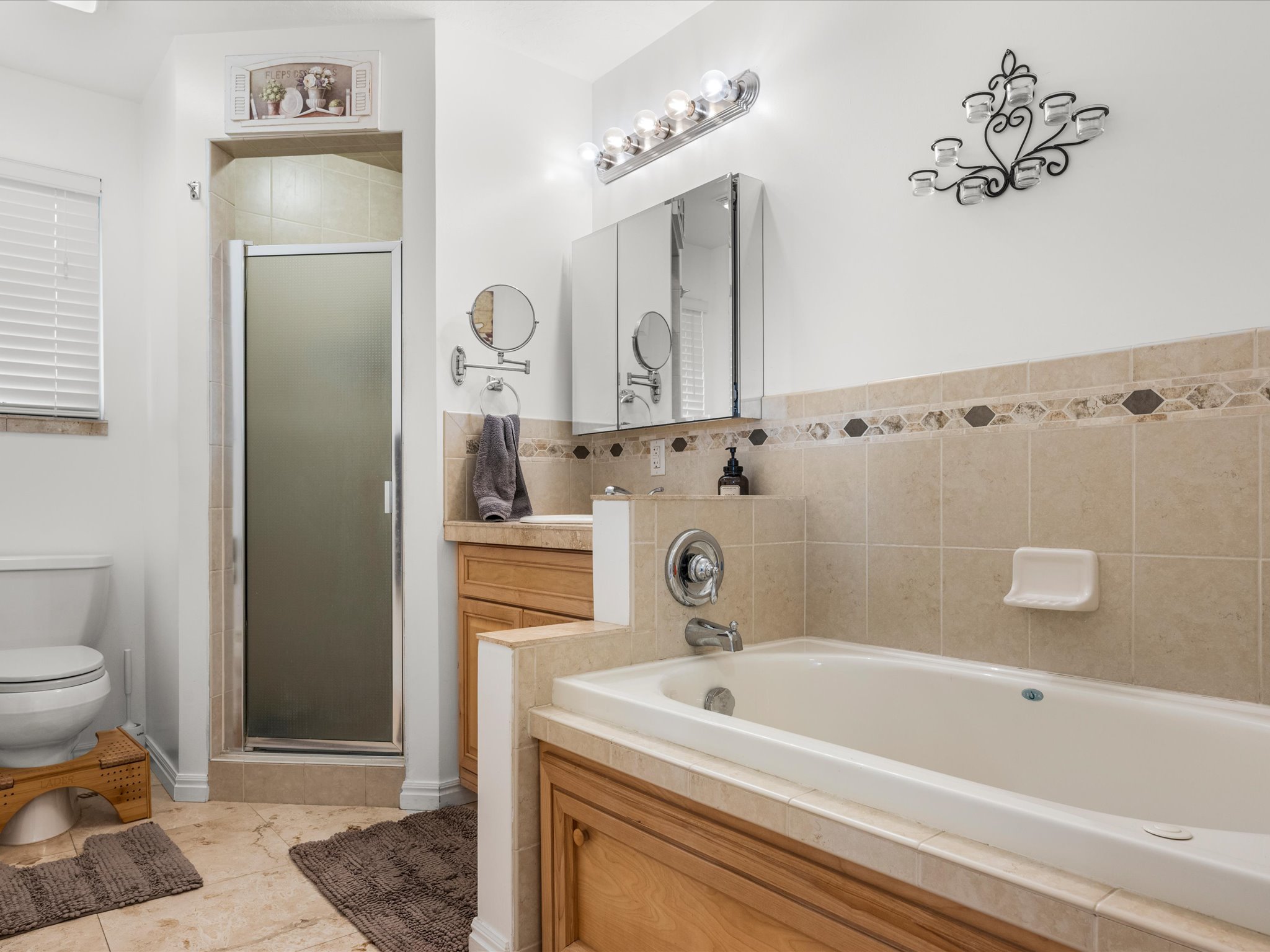 Bathroom featuring a built-in tub, separate enclosed shower, dual vanity with wood cabinetry, and tiled flooring