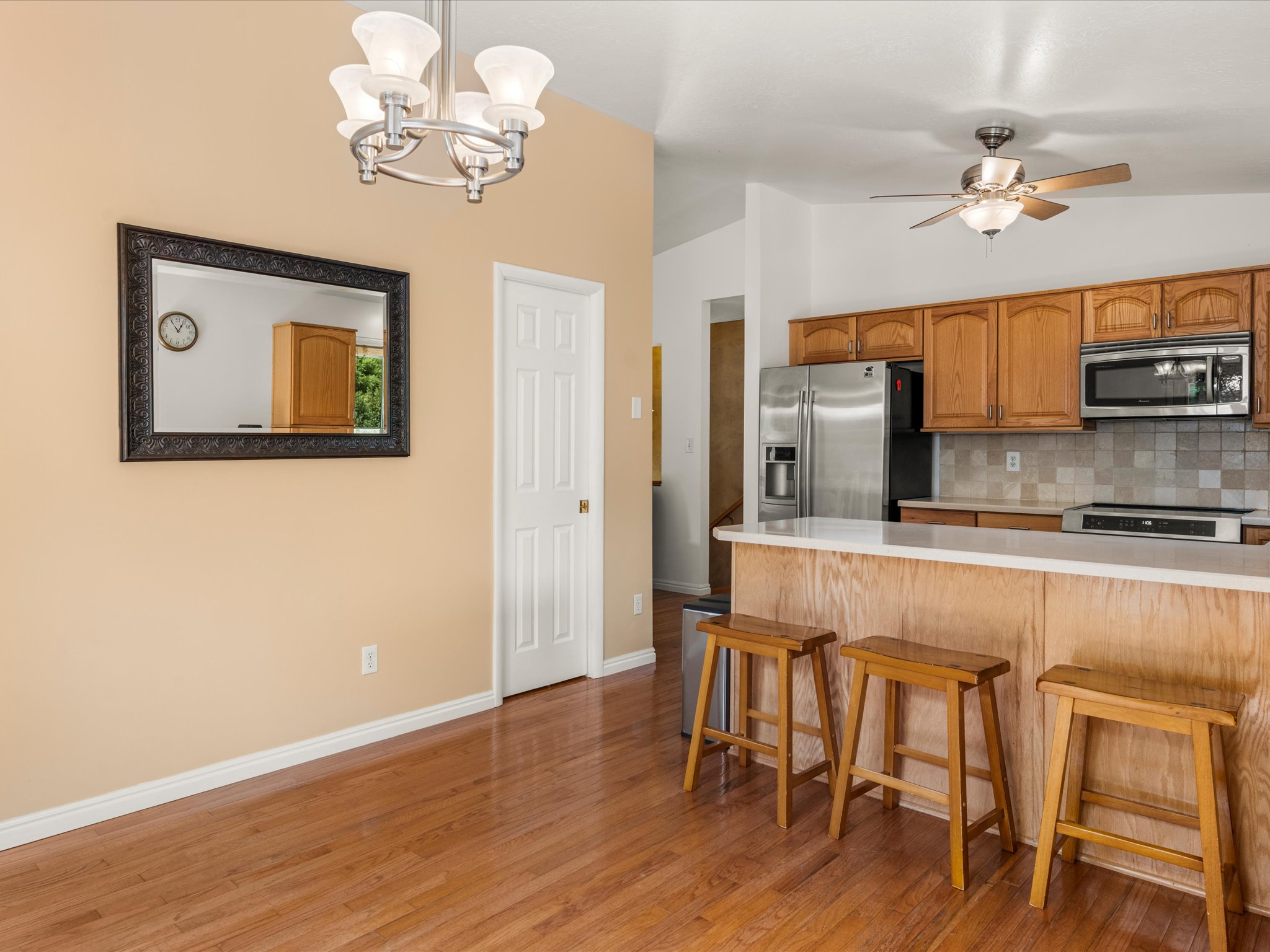 Open-concept kitchen and dining area featuring wood-finish flooring, a breakfast bar, stainless steel appliances, and a tile backsplash