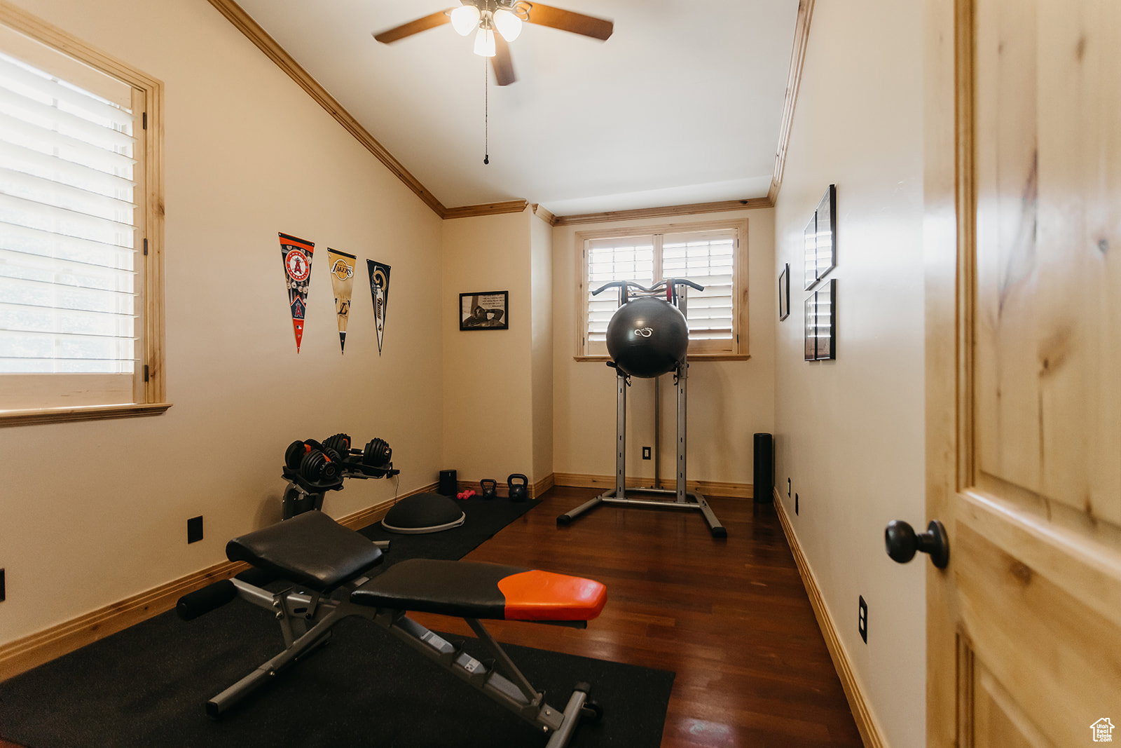 Interior room featuring wood-finish flooring, natural wood window trim, and a ceiling fan with integrated lighting