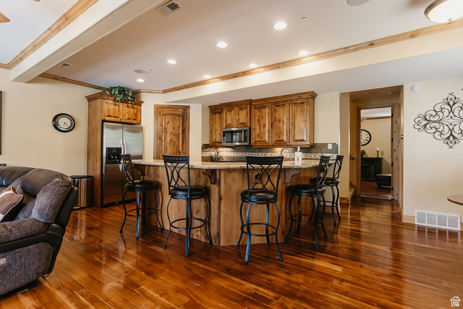 Gourmet kitchen featuring wood-finish cabinetry, stainless steel appliances, and a breakfast bar with stone countertops