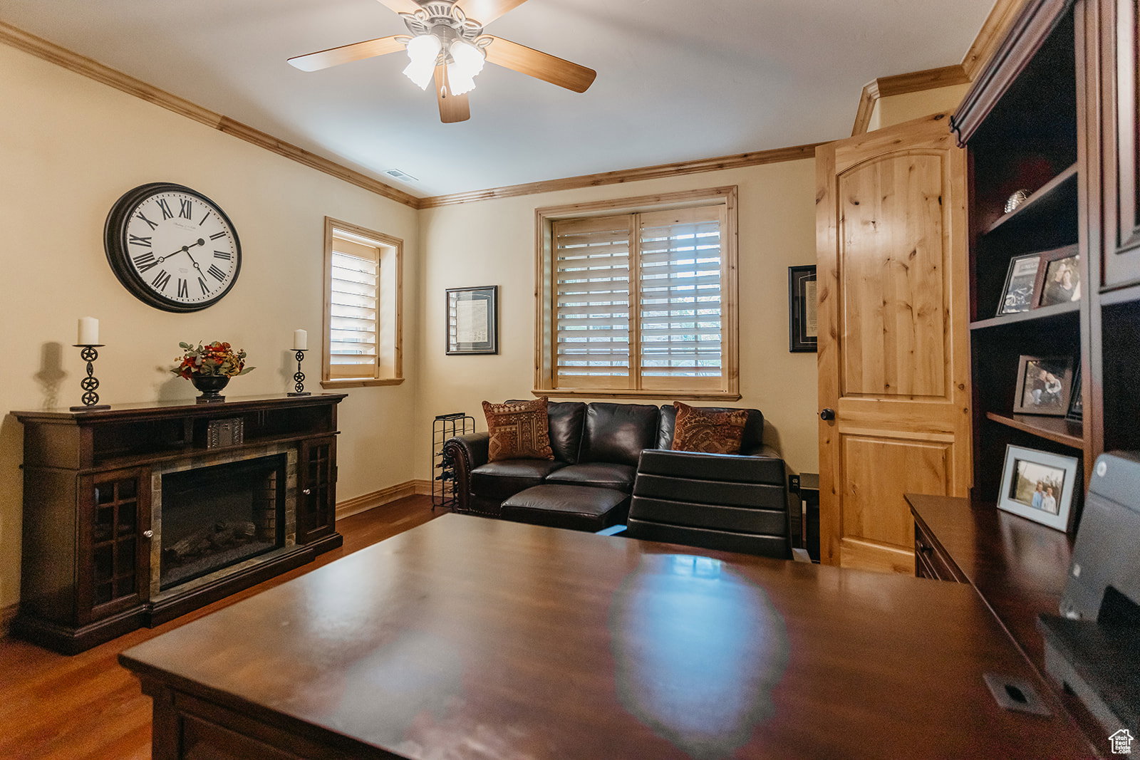 Warmly appointed room featuring wood-finish flooring, wood trim, and a ceiling fan with integrated lighting