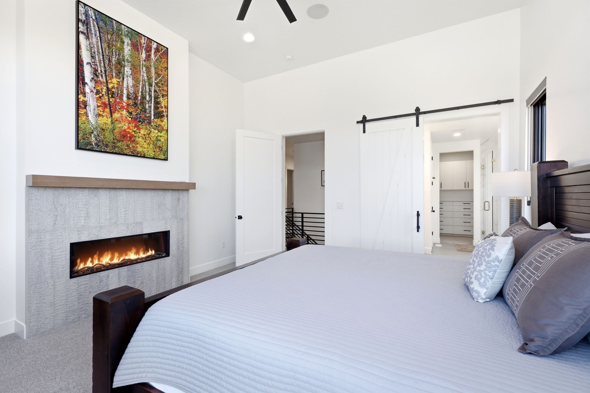 Bedroom featuring a horizontal linear fireplace with a light-toned tile surround and a wood mantel