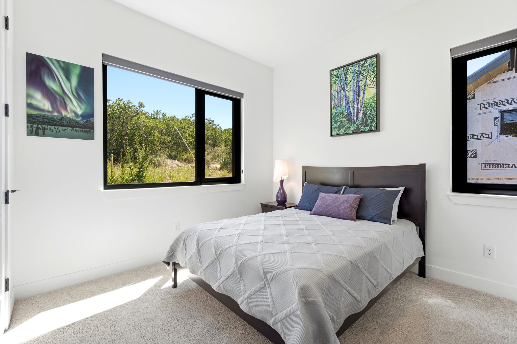 Bedroom featuring a large horizontal window and a smaller vertical window, both with black framing