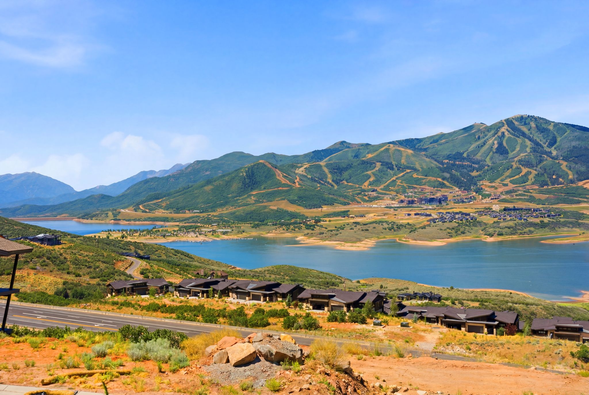 Expansive lake and mountain scenery featuring a large body of water, distant mountain ranges, and residential structures