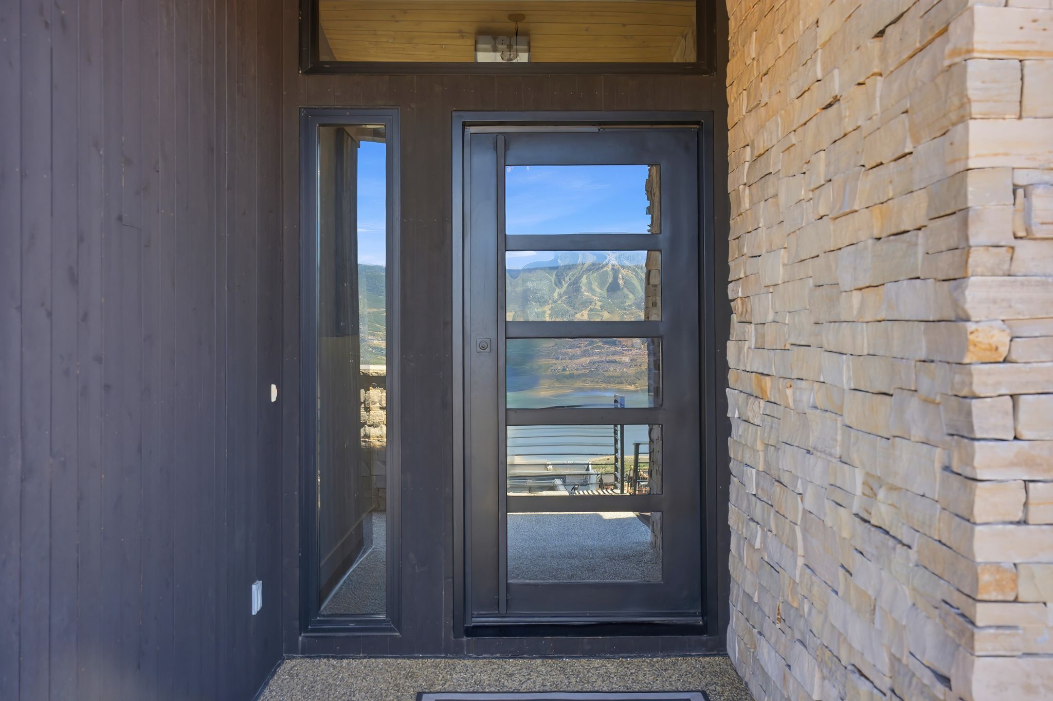 Modern entry door featuring multiple glass panels, complemented by a sidelight and transom window
