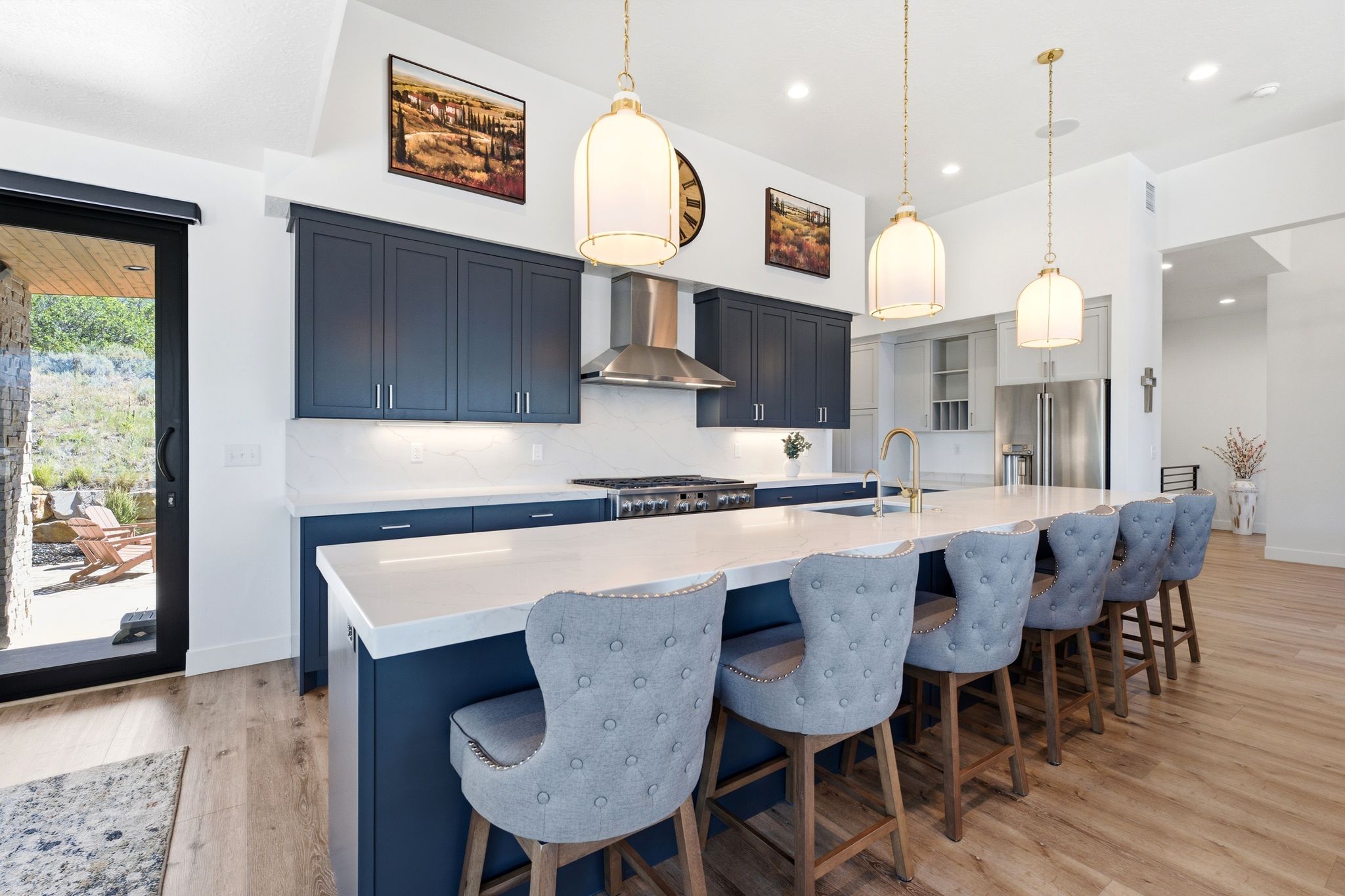 Spacious kitchen featuring an extended island with a light-toned countertop, deep blue cabinetry, stainless steel appliances, and wood-finish flooring
