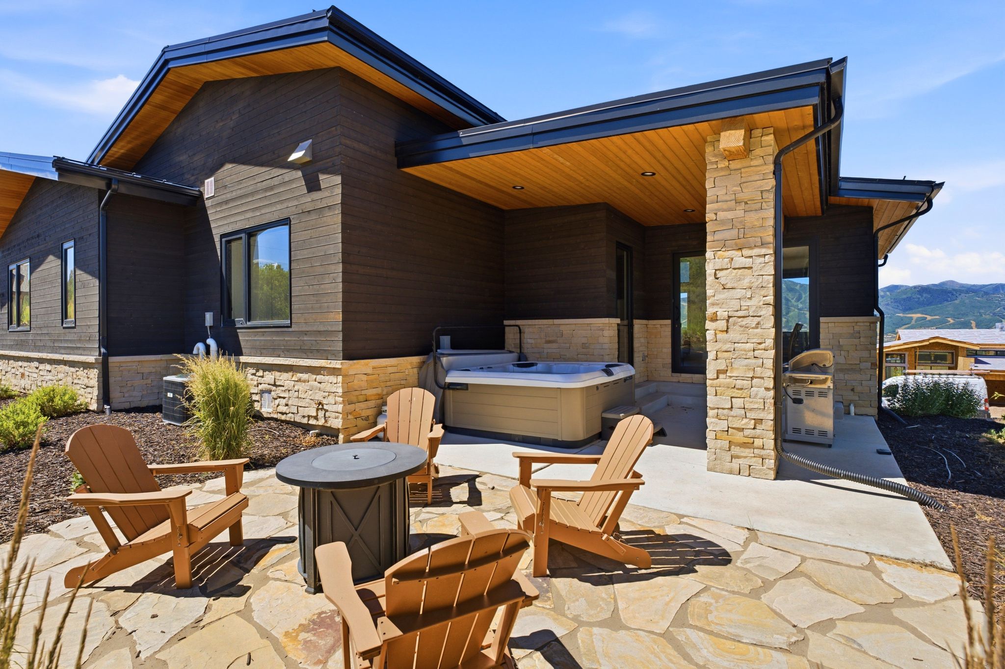 Outdoor patio featuring flagstone and concrete surfaces, a built-in spa, and a stone-clad structural support column