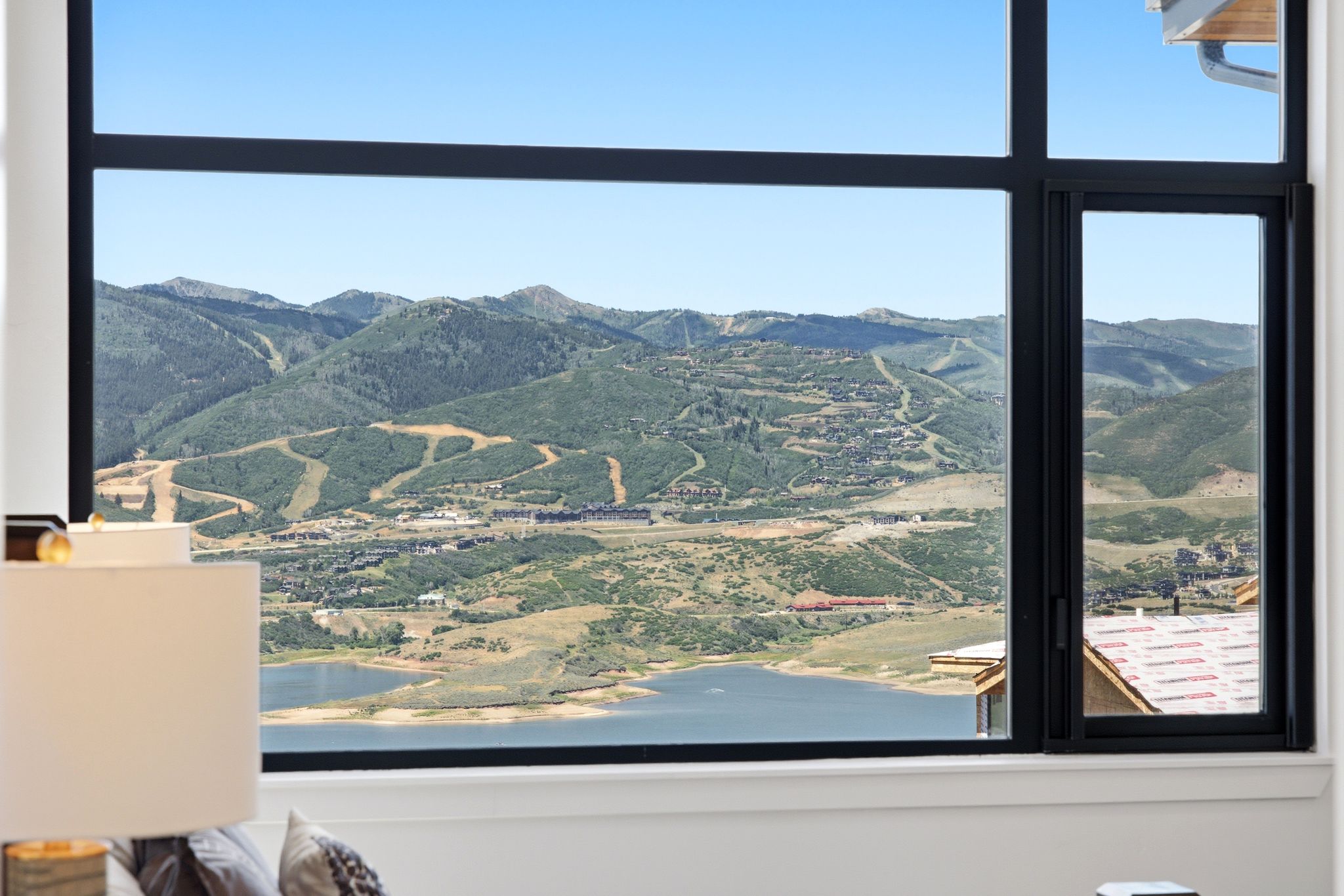 Expansive black-framed window offering panoramic mountain and lake scenery